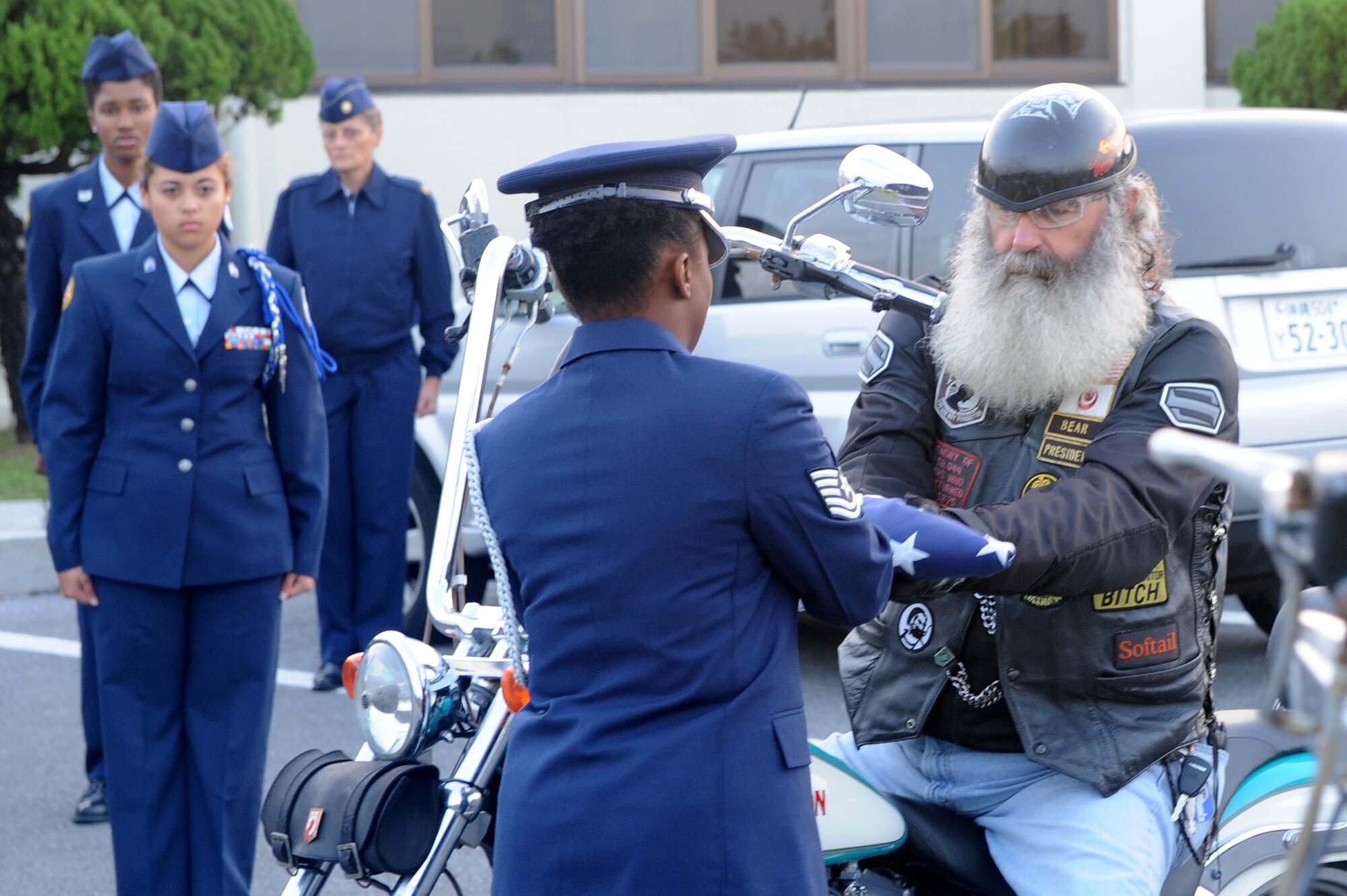 A member of the Okinawan Vietnam Veterans Motorcycle Club presents the United States flag to a member of the Kadena Honor Guard during the Veterans Day ceremony at Kadena Air Base, Japan, Nov. 11, 2014. As part of the Veterans Day ceremony, members of the club performed a drive by with the American flag. (U.S. Air Force photo by Airman 1st Class Stephen G. Eigel/Released)