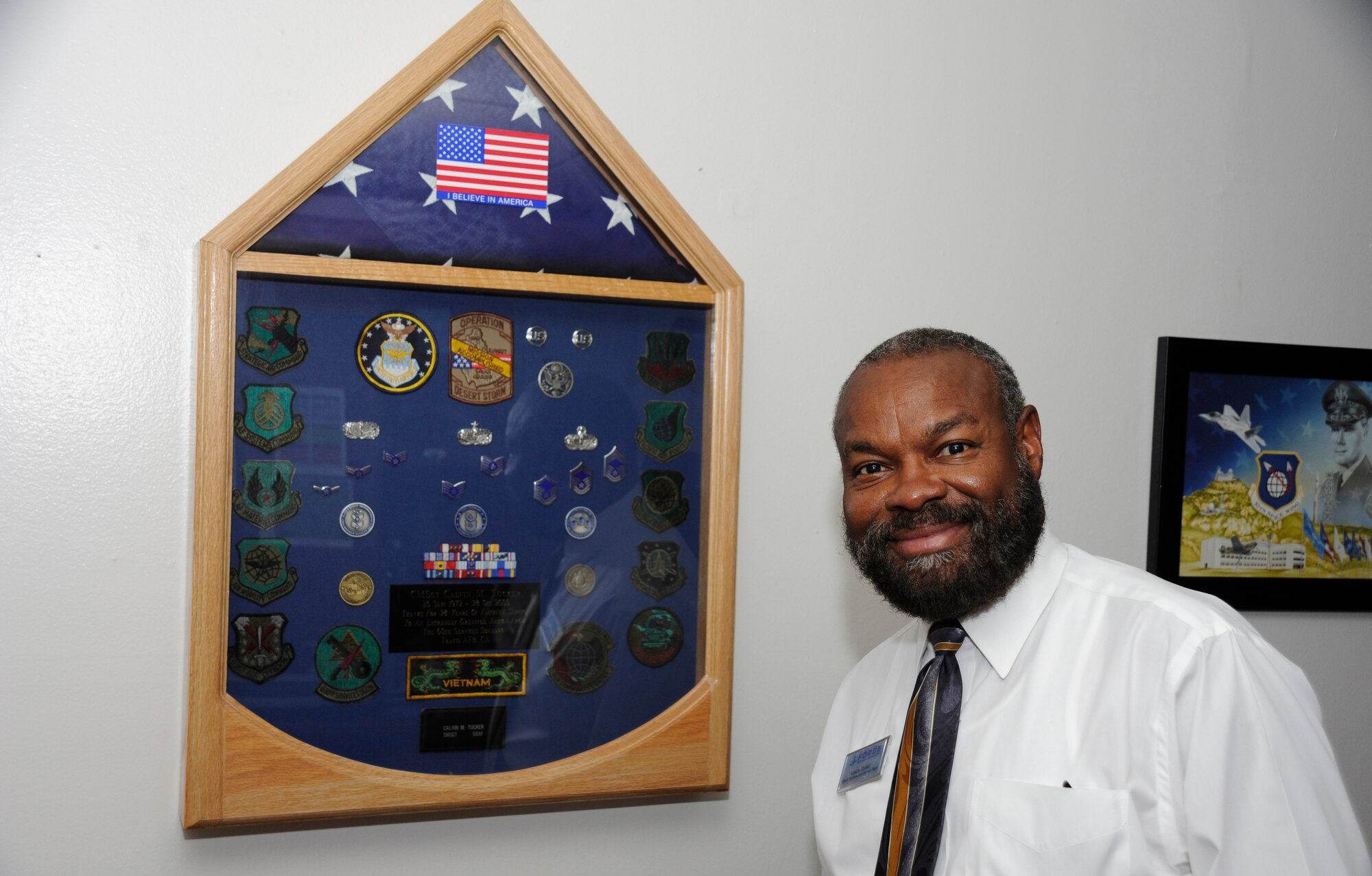 Calvin Tucker, 30th Force Support Squadron chief of sustainment services flight, poses next to his shadow box containing his military accomplishments, Nov. 7, 2014, Vandenberg Air Force Base, Calif. Veterans Day is a nationally celebrated holiday that honors those who have served in the United States Armed Forces. (U.S. Air Force photo by Airman Robert J. Volio/Released)