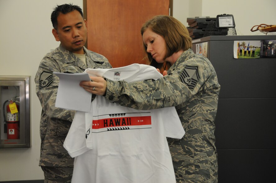 U.S. Air Force Senior Master Sgt. Virgilio M. Salvador, 154th Maintenance Squadron, Hawaii Air National Guard, presents Master Sgt. Adrianne Schulz, executive assistant to command chief master sgt. of the Air National Guard, with a squadron t-shirt during her visit to the 154th Wing at Joint Base Pearl Harbor Hickam on Nov. 5, 2014. On the back of the shirt is a "94" which represents the year the squadron was formed. (U.S. Air Force photo by Airman 1st Class Robert Cabuco)
