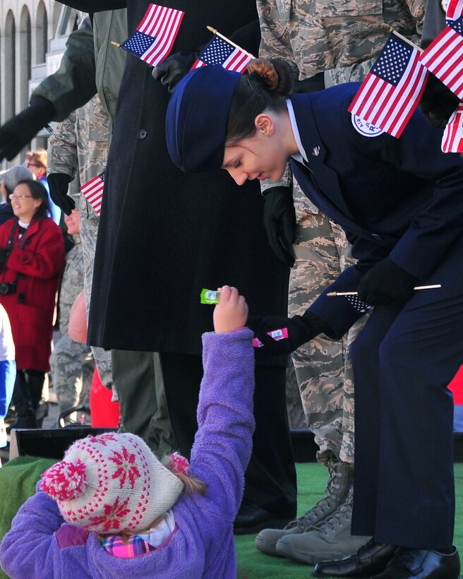 Avery Tibbets accepts a piece of candy from a young spectator at the annual Veterans Day Parade Nov. 8. Avery is the daughter of Brig. Gen. Paul W. Tibbets deputy director, nuclear operations at U.S. Strategic Command and is a senior ROTC member at Bellevue West High School. (U.S. Air Force photo by D.P. Heard/Released)