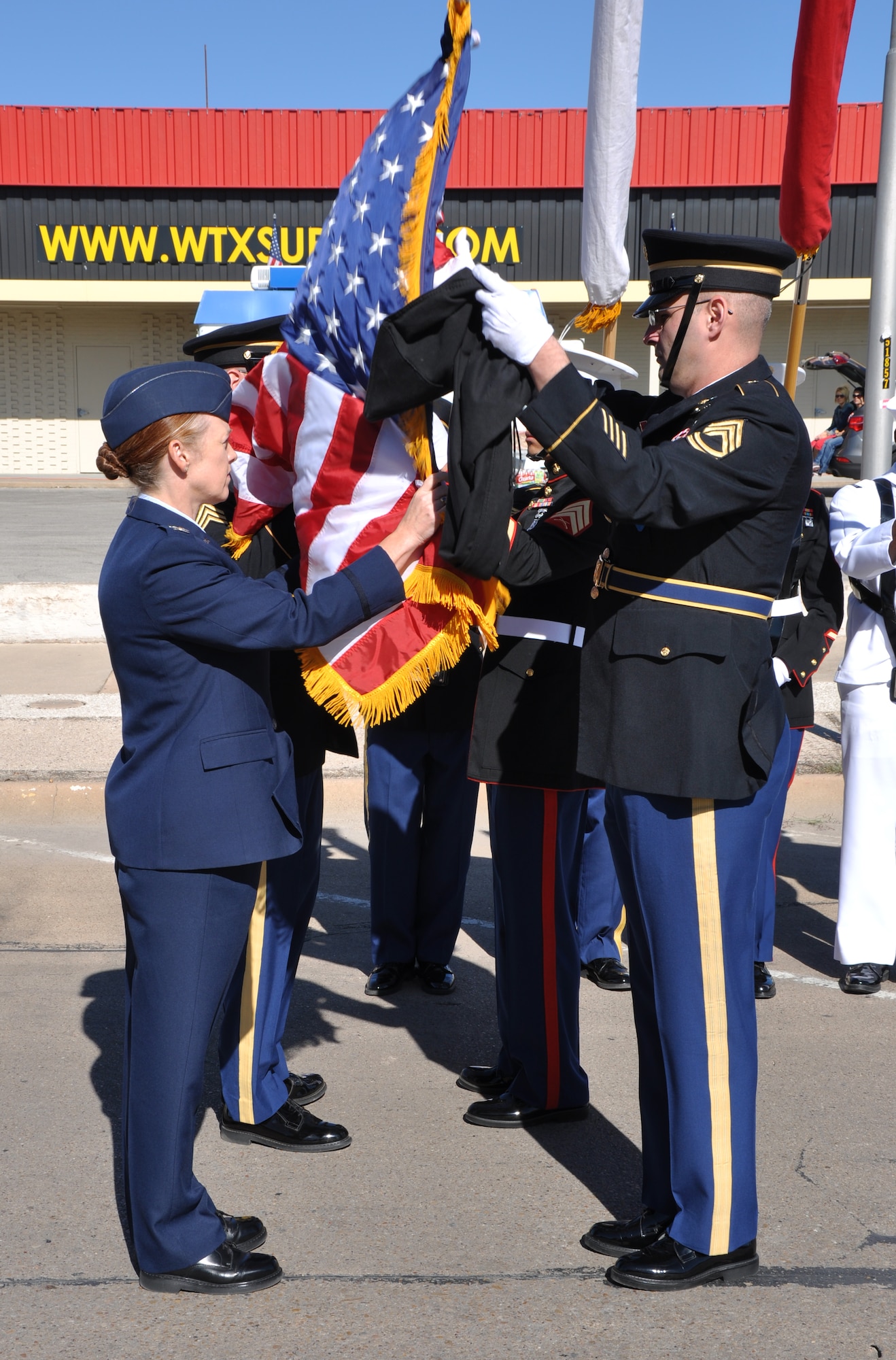 SAN ANGELO, Texas – Col. Kimberlee P. Joos, 17th Training Wing Commander, and Goodfellow’s Joint Service Color Guard unfurl the American flag before the Veterans Day parade downtown Nov. 8. Joos and the color guard also unfurled an Army, Marine Corps, Navy and Air Force flag. (U.S. Air Force photo/ Senior Airman Joshua Edwards)