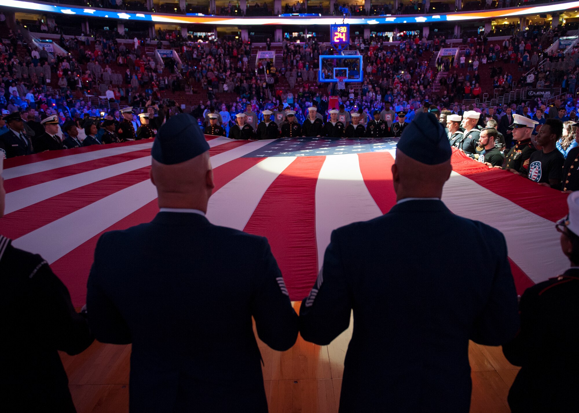 Airmen, Soldiers, Sailors, Marines and Coast Guardsmen hold a large American flag during the singing of the “Star Spangled Banner,” prior to the start of a Chicago Bulls versus Philadelphia 76ers basketball game Nov. 7, 2014, at the Wells Fargo Center, in Philadelphia. The 76ers organization provided free tickets to hundreds of service members from local military instillations, including Dover Air Force Base, Del. and Joint Base McGuire-Dix-Lakehurst, N.J. (U.S. Air Force photo/Airman 1st Class Zachary Cacicia)
