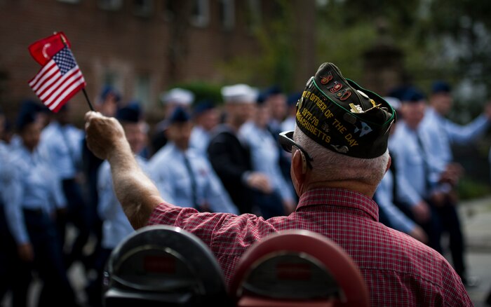 U.S. Marine Corps veteran Richard Starr waves an American flag as members of Joint Base Charleston march by while participating in the Ralph H. Johnson Veterans Hospital Annual Veterans Day parade Nov. 8, 2014, in Charleston, S.C. The origins of the holiday date back to President Woodrow Wilson, who proclaimed Armistice Day to mark the end of World War I. The armistice between Germany and the Allied nations that ended WWI was signed on that day and a ceasefire went into effect on the 11th hour of the 11th day of the 11th month in 1918. (U.S. Air Force photo/Airman 1st Class Clayton Cupit)