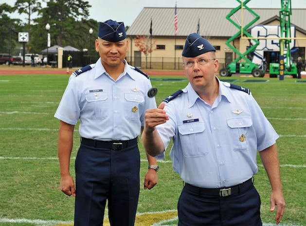 Colonel Jimmy Canlas, 437th Airlift Wing vice commander, watches as Col. Jeffrey DeVore, Joint Base Charleston commander, flips a ceremonial coin as part of the military appreciation day pre-game activities Nov. 8, 2014, on the Charleston Southern University Campus in Goose Creek, S.C. The CSU Buccaneers defeated Gardner-Webb  44-14. (Courtesy photo/Jim Killian)