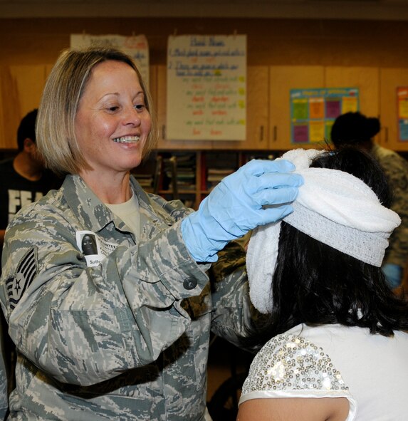 Tech. Sgt. Karen Fletcher applies gauze to a student’s simulated head injury at Sutton Elementary School in Fort Smith, Ark., Oct. 30, 2014. Airmen from the 188th Wing volunteered to participate in the fall festival MASH Bash through the local Partners in Education program. Fletcher is assigned to the 188th Logistics Readiness Squadron. (U.S. Air National Guard photo by Staff Sgt. Hannah Landeros/released)