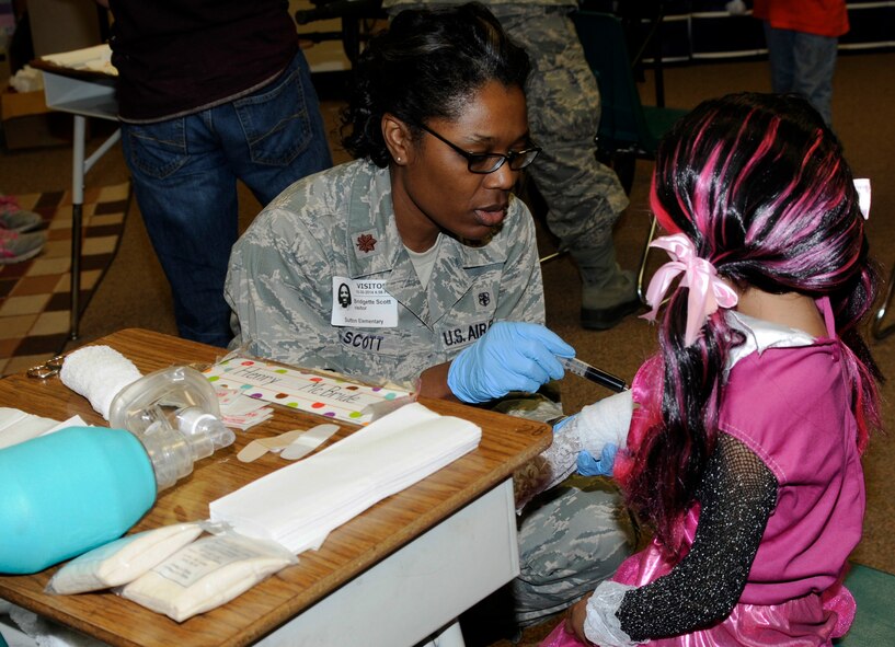 Maj. Bridgette Scott dresses a student’s simulated wound during the fall festival MASH Bash at Sutton Elementary School in Fort Smith, Ark., Oct. 30, 2014. Scott is assigned to the 188th Medical Group. Sutton Elementary has teamed up with the 188th Wing through the local Partners in Education program which allows unit members to teach children about jobs and personal experiences in the Air Force through events like MASH Bash and annual career days. (U.S. Air National Guard photo by Staff Sgt. Hannah Landeros/released)