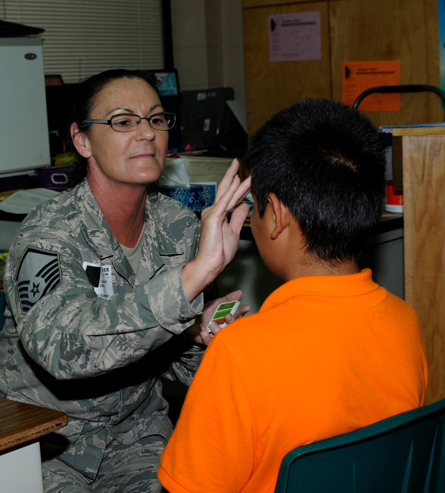 Master Sgt. Lanette Hunt applies camouflage face paint to a student during a fall festival MASH Bash at Sutton Elementary School in Fort Smith, Ark., Oct. 30, 2014. Airmen from the 188th Wing volunteered to assist students in the community through the local Partners in Education program. Hunt is assigned to the 188th Communications Flight. (U.S. Air National Guard photo by Staff Sgt. Hannah Landeros/released)