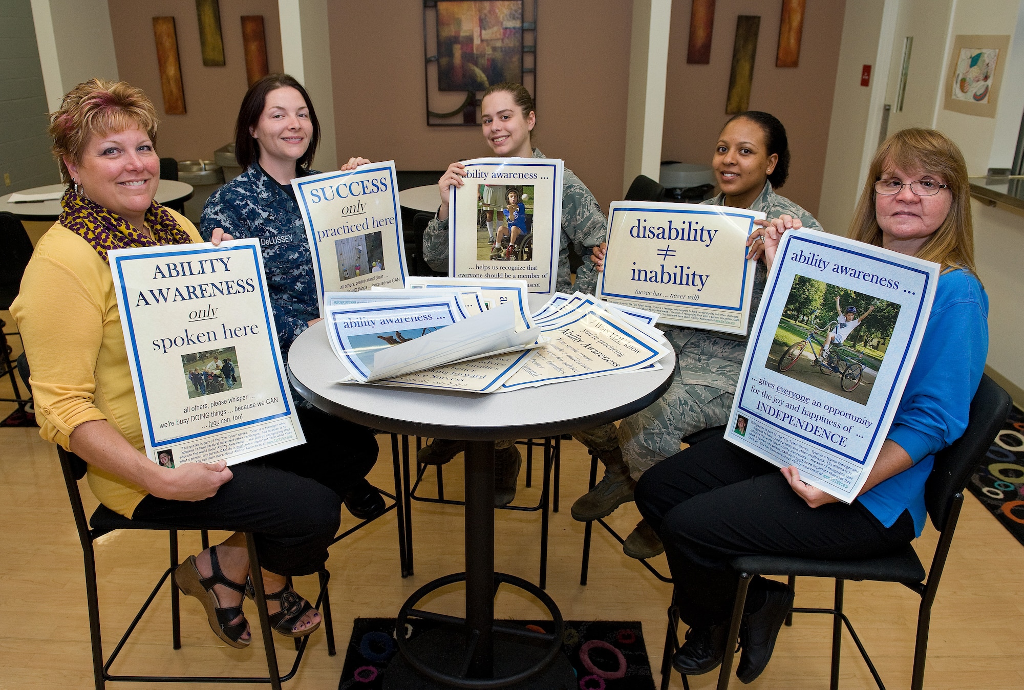 National Disability Employment Awareness Month committee members hold up ability awareness posters Oct. 7, 2014, at the Youth Center on Dover Air Force Base, Del. Committee members placed the posters in numerous work areas across the base as part of the effort to bring awareness to people having abilities rather than disabilities. (U.S. Air Force photo/Roland Balik)