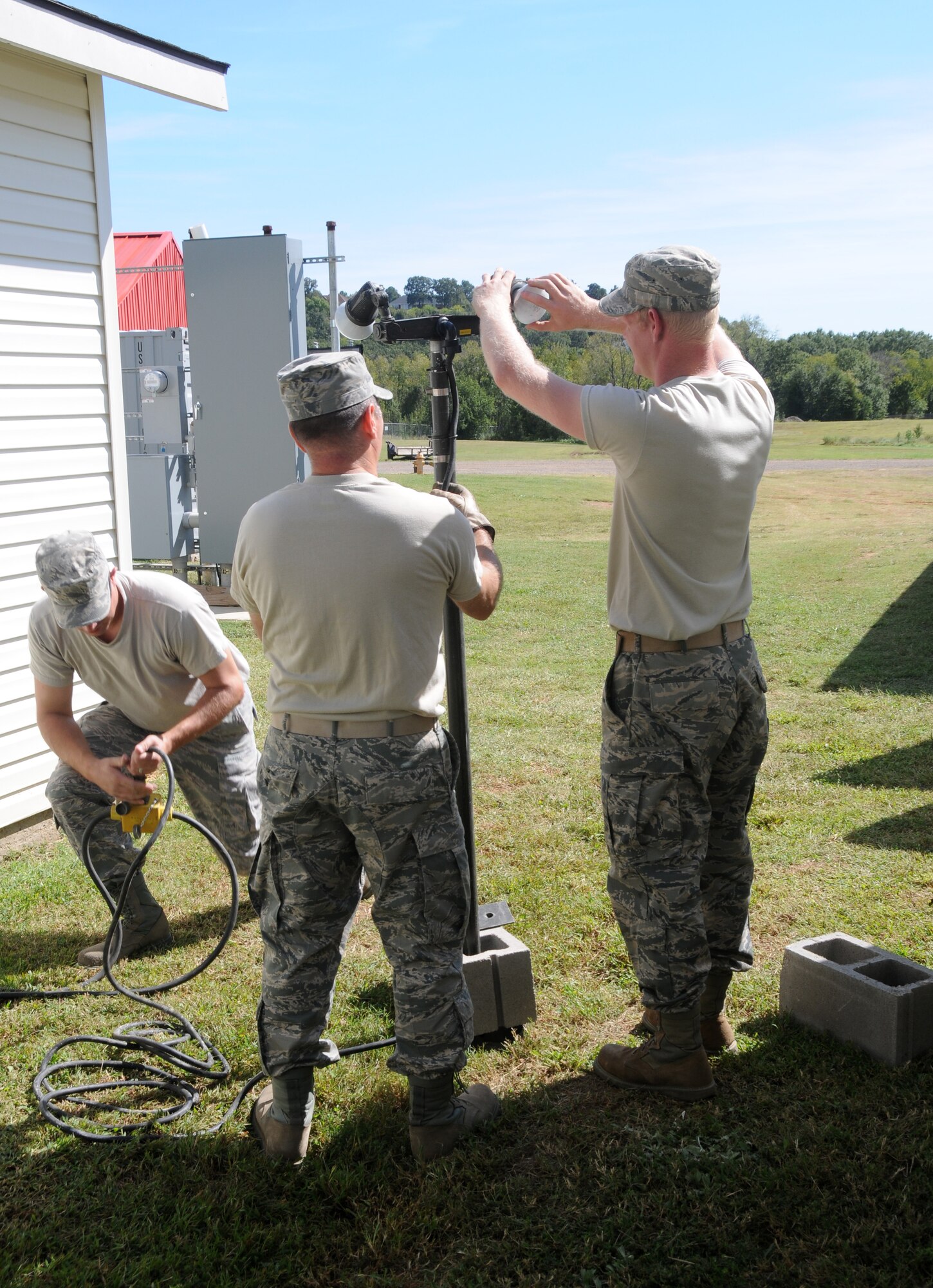 Staff Sgt. Tobee Chandler, Staff Sgt. Grant Baskette and Senior Airman David Swearingen assemble an outdoor lighting unit during a bivouac training exercise held at Ebbing Air National Guard Base, Fort Smith, Ark., Oct. 4, 2014. The three Airmen are members of the 188th Civil Engineering Squadron. (U.S. Air National Guard photo by Airman 1st Class Cody Martin/released)