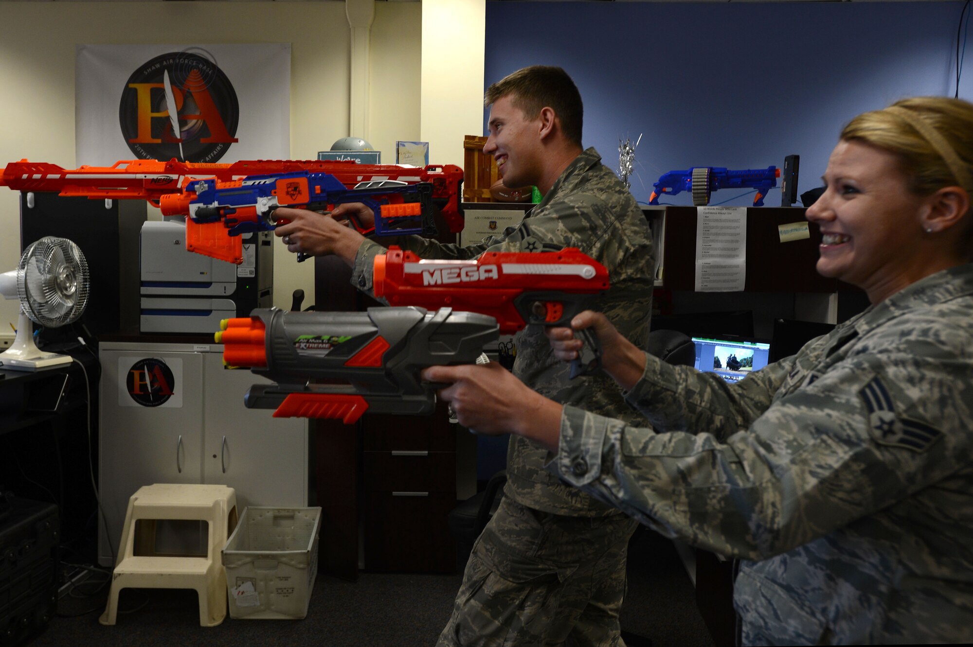 U.S. Air Force Senior Airman Tabatha Zarrella and Airman 1st Class Michael Cossaboom, 20th Fighter Wing Public Affairs photojournalists, participate in an office NERF battle Nov. 7, 2014, at Shaw Air Force Base, S.C. Maintaining the social pillar of Comprehensive Airman Fitness while in a work setting ensures personal and professional success and resiliency of the Airmen in the public affairs office. CAF’s pillars of fitness include mental, physical, social, and spiritual. (U.S. Air Force photo by Airman 1st Class Jensen Stidham/Released)
