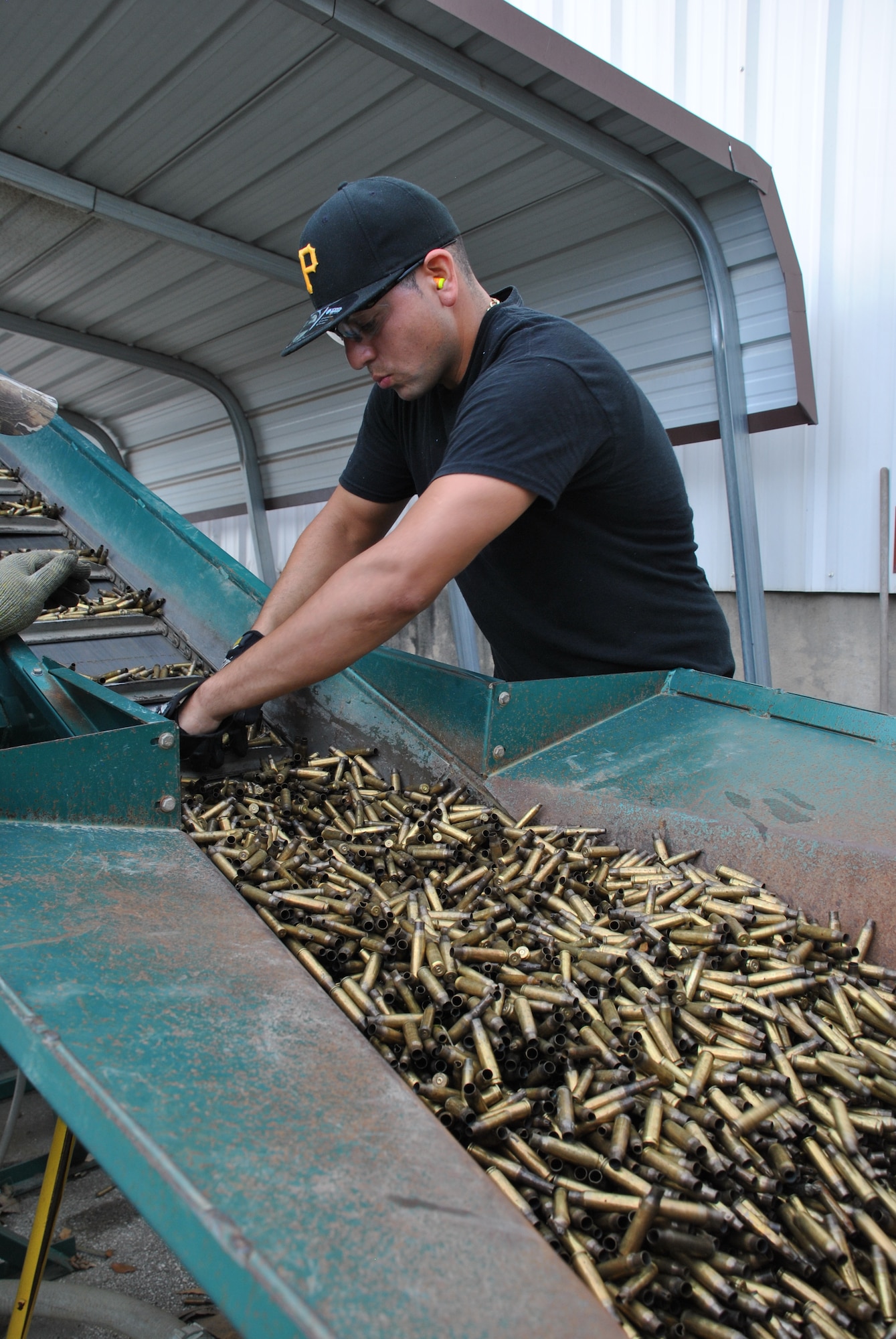 A Joint Base San Antonio-Lackland Recycling Center worker examines ammunition brass as part of the base’s recycling effort. The installation operates a zero-cost recycling program, with recycling proceeds used to pay worker salaries and the facility’s operating and maintenance costs. (U.S. Air Force photo/Jennifer Schneider/Released)