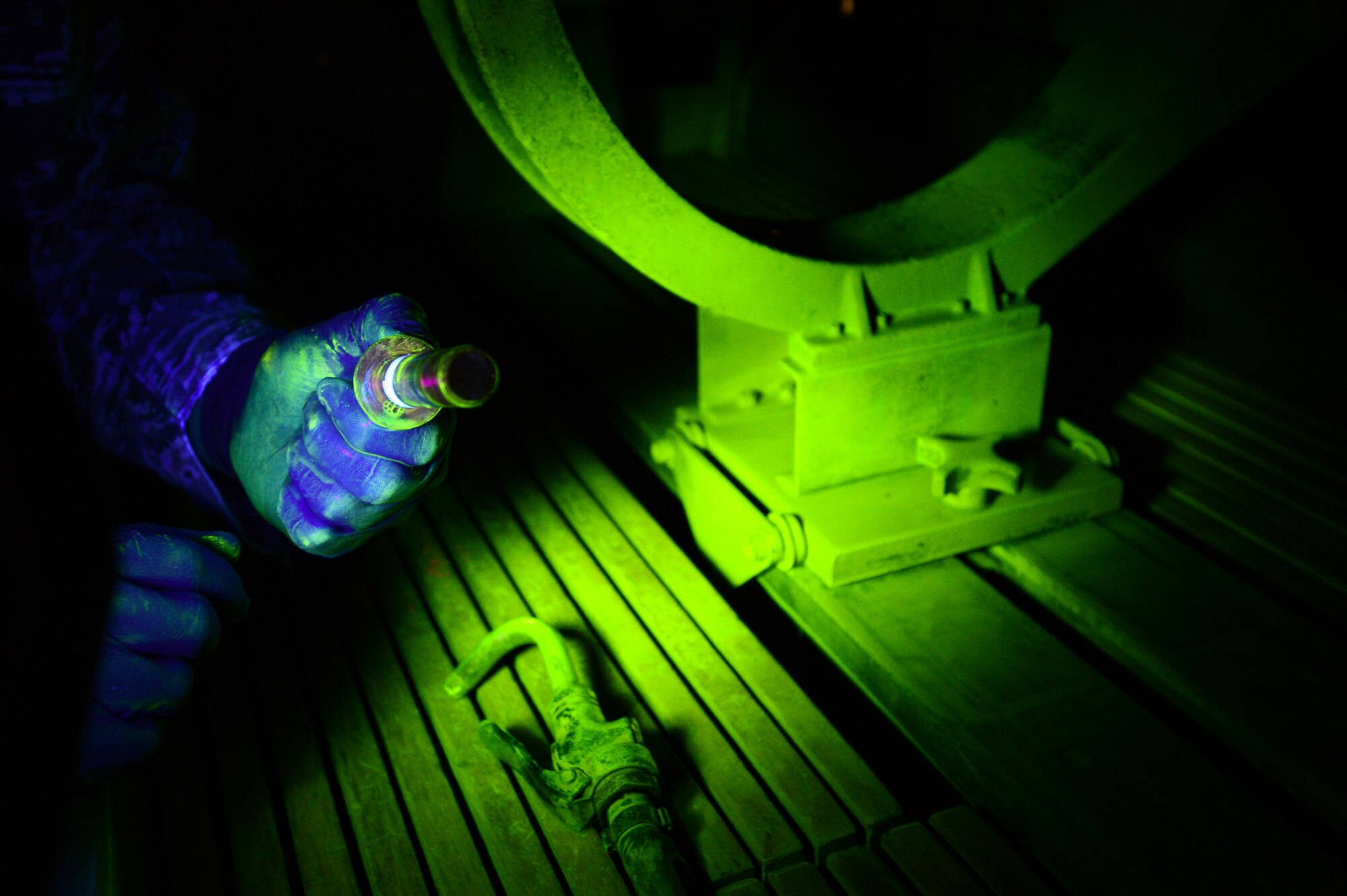 An U.S. Air Force Airman assigned to the 20th Equipment Maintenance Squadron non-destructive inspection shop, holds a magnetized F-16CM Fighting Falcon wing attachment bolt during a magnetic particle inspection at Shaw Air Force Base, S.C., Nov. 3, 2014. During the inspection, fluorescent magnetized particles fill any cracks in the bolt, making the cracks visible under a black light. (U.S. Air Force photo by Airman 1st Class Jensen Stidham/Released) 