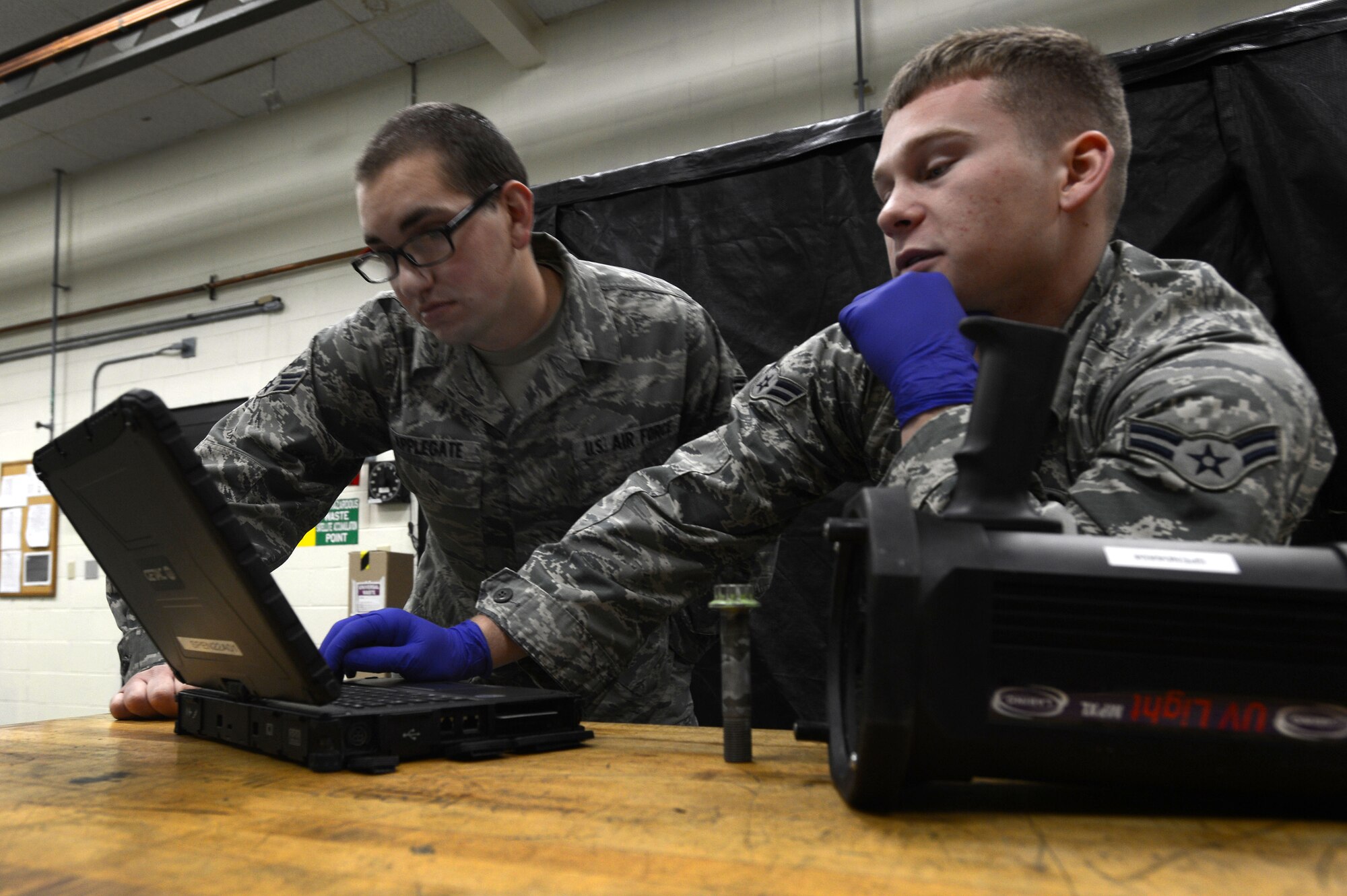 (From left) U.S. Air Force Senior Airman Zachary Applegate and Airman 1st Class Logan Young, 20th Equipment Maintenance Squadron non-destructive inspection technicians, view a technical order at Shaw Air Force Base, S.C., Nov. 3, 2014. Before inspecting any part, NDI Airmen read the TO, ensuring they follow any special instructions regarding the part. (U.S. Air Force photo by Airman 1st Class Jensen Stidham/Released)  