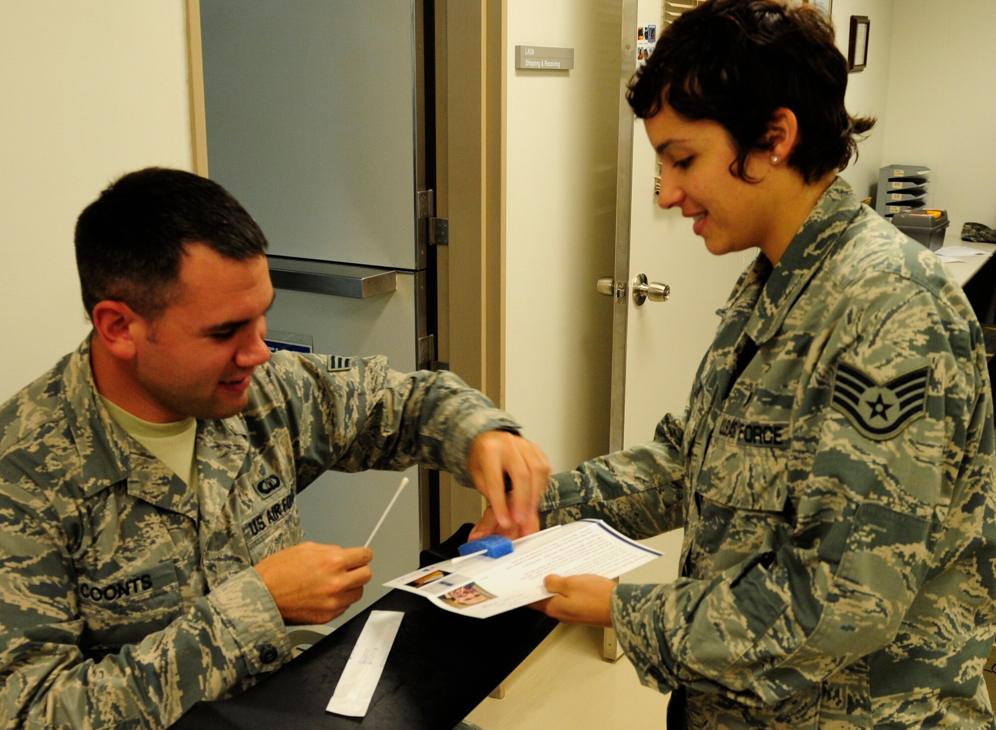 U.S. Air Force Staff Sgt. Taniah Otis (right), 18th Medical Support Squadron NCO in-charge of microbiology, assists Senior Airman Aaron Coonts (left), 18th Operation Support Squadron air traffic control journeyman, with filling out his application for the C.W. Bill Young Department of Defense Marrow Donor Program on Kadena Air Base, Japan, Nov.4, 2014. Last year's drive produced more than 900 members applying. When members register, they are put on a list of possible matches to potentially donate bone marrow in the future if found compatible with a patient in need. (U.S. Air Force photo by Airman 1st Class Keith James/Released)