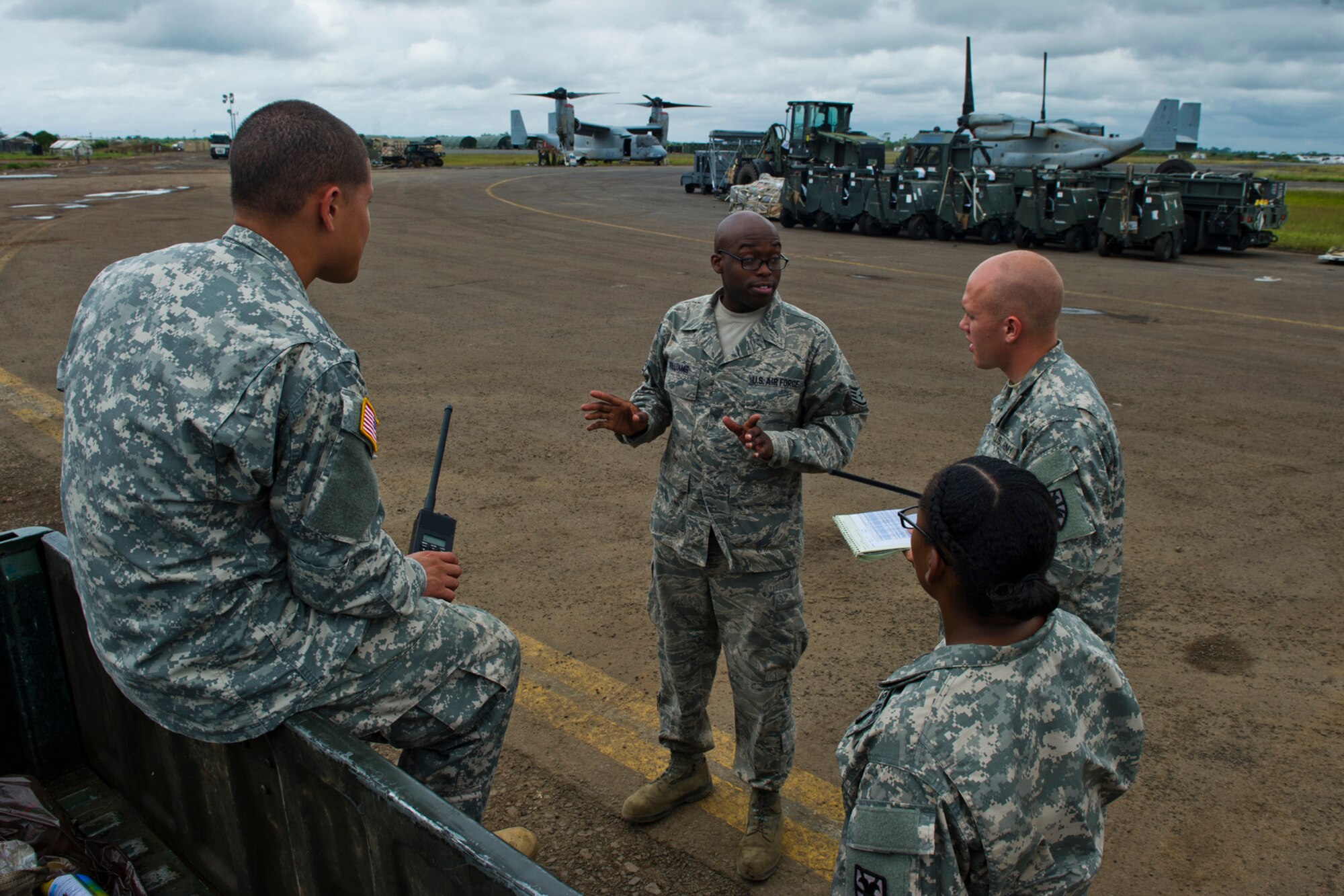 U.S. Air Force Staff Sgt. Marquis Williams (middle) from the Joint Task Force-Port Opening assigned to the 621st Contingency Response Wing stationed at Joint Base McGuire-Dix-Lakehurst, N.J., talks to members of the 101st Airborne Division about flightline procedures to help prepare them to take over the cargo distribution mission at Roberts International Airport, Republic of Liberia, during Operation UNITED ASSISTANCE, Nov. 9, 2014. The JTF-PO established a hub for cargo distribution to help alleviate the increased traffic of airflow and cargo during OUA, a Department of Defense operation in Liberia to provide logistics, training and engineering support to U.S. Agency for International Development-led efforts to contain the Ebola virus outbreak in western Africa. (U.S. Air Force photo/Staff Sgt. Gustavo Gonzalez/RELEASED)