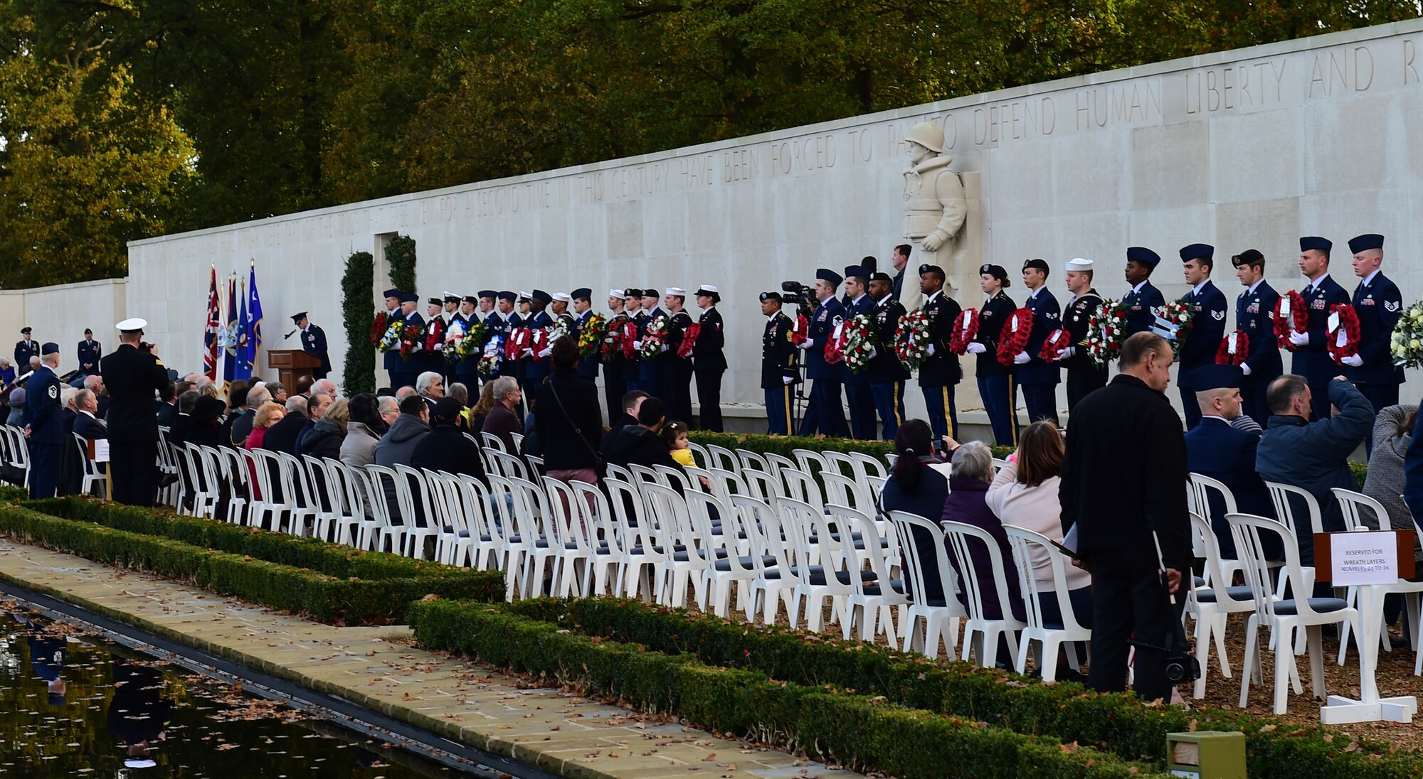 Service members from the 501st Combat Support Wing stand before a crowd of more than 50 guests during a Veterans Day ceremony at Cambridge American Cemetery, United Kingdom, Nov. 11, 2014. The Service members bore donated wreaths during the ceremony to recognize veterans both past and present. (U.S. Air Force photo by Tech. Sgt. Chrissy Best/Released)