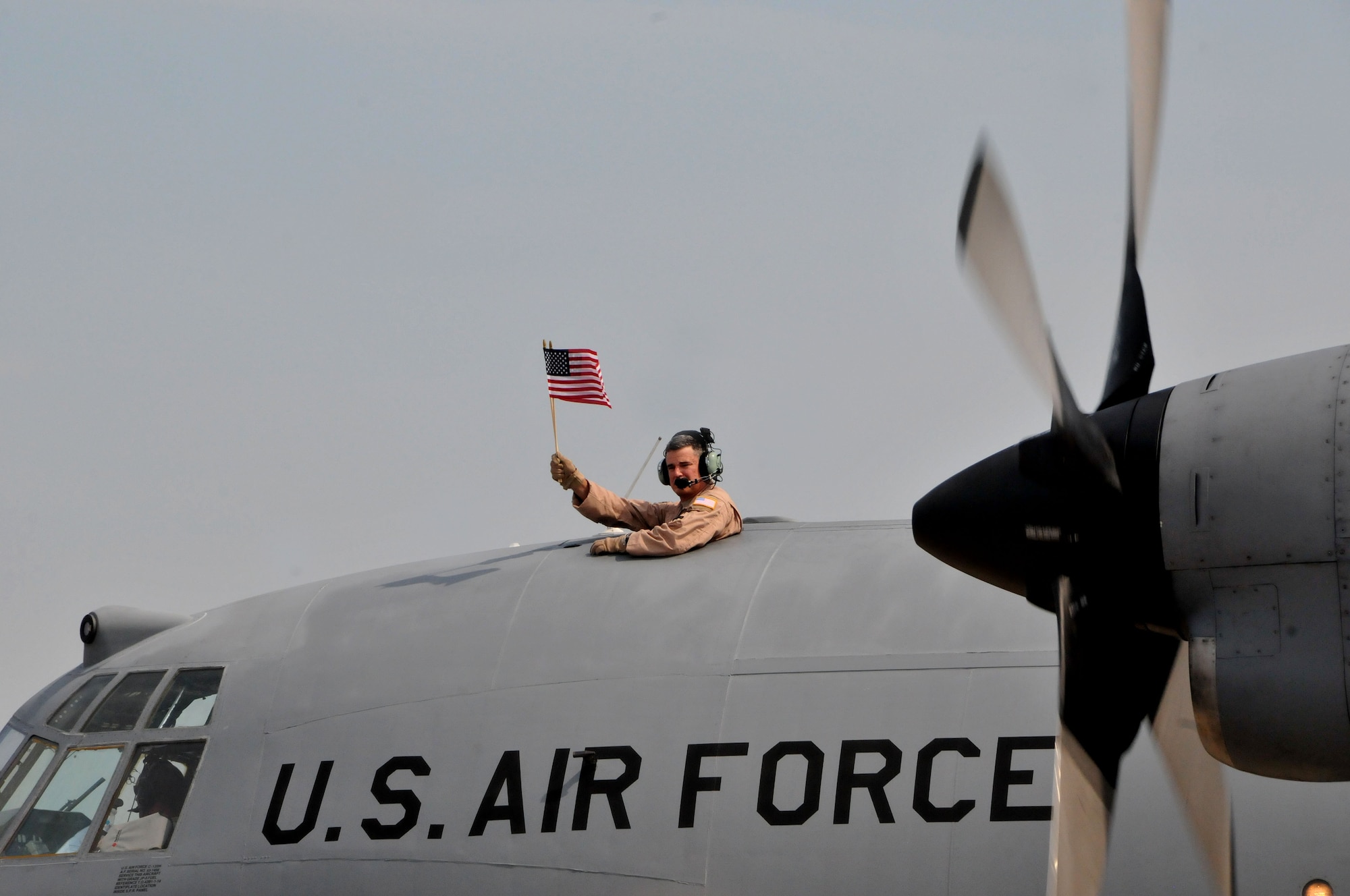 U.S. Air Force Staff Sgt. Rob Levings, Flight Engineer for the 145th Operations Support Squadron, waves an American flag, saying goodbye to family and friends as he and other airmen from the 145th Airlift Wing deploy to Southwest Asia. The C-130 Hercules aircraft departed from the North Carolina Air National Guard base, Charlotte Douglas Intl Airport, June 26, 2014. (U.S. Air National Guard photo by Master Sgt. Patricia F. Moran, 145th Public Affairs/Released) 

