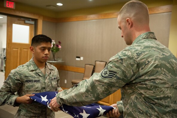 Staff Sgt. Fernado Andres-Miguel, 694th Intelligence Support Squadron knowledge operations manager, and Staff Sgt. Thomas Comerford, 7th Air Force NCO in charge of intelligence, surveillance and reconnaissance combat plans and exercise, practice folding an American flag during Honor Guard practice at Osan Air Base, Republic of Korea, Oct. 30, 2014. The folding of the flag ceremony is one of the ceremonies performed during retirements. (U.S. Air Force photo by Senior Airman Matthew Lancaster)