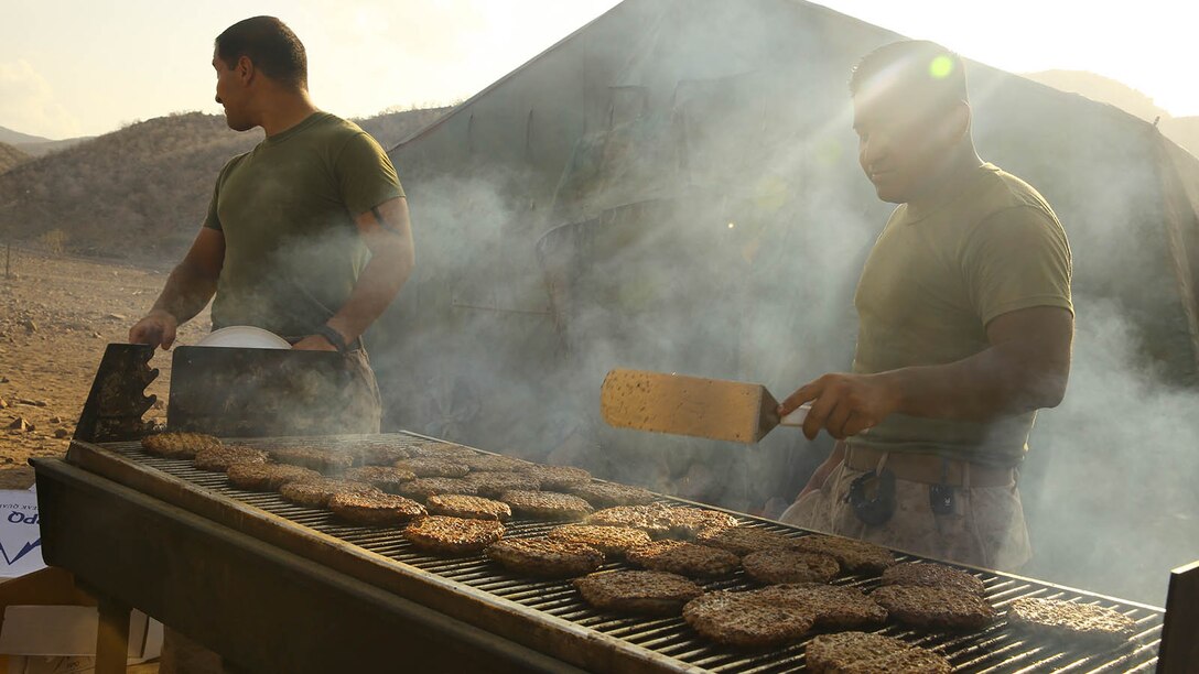 U.S. Marine Corps Sgt. Mario V. Castillo, right, a food service specialist with the 11th Marine Expeditionary Unit (MEU), and native of Escondido, California, grills hamburgers for the 239th birthday of the United States Marine Corps during sustainment training in D'Arta Plage, Djibouti, Nov. 10. The 11th MEU is deployed as a theater reserve and crisis response force throughout U.S. Central Command and 5th Fleet area of responsibility. 