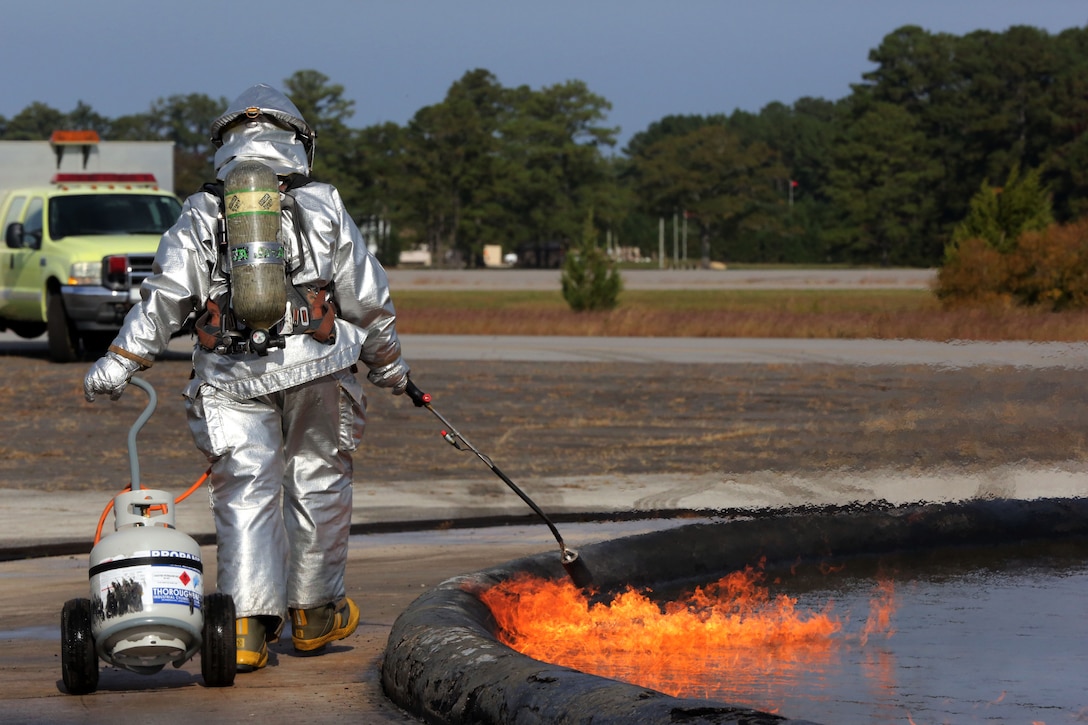 Lance Cpl. Ana Beylar lights a fire pit during P-19 P-19R evaluations at Marine Corps Air Station Cherry Point N.C., Oct. 28, 2014. Beylar is an aircraft rescue firefighter with Headquarters and Headquarters Squadron. Beyler is a native of Fishers, Ind. 