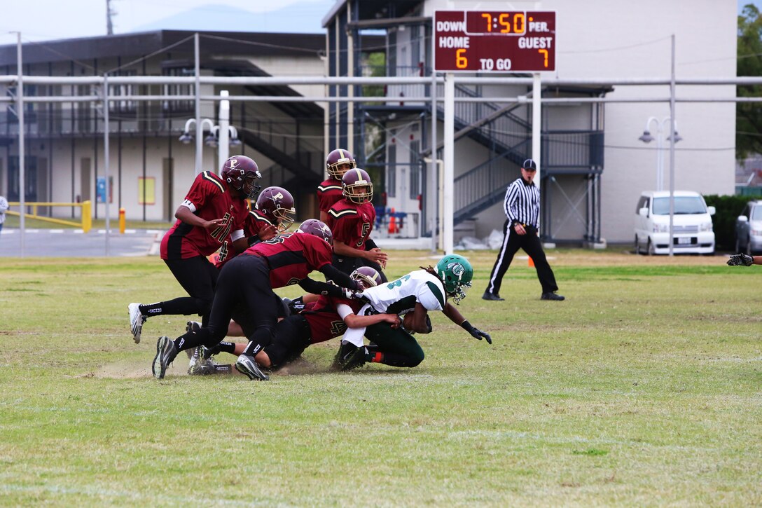 A swarm of Matthew C. Perry Samurai football players tackle DeMarco Andrews, a Daegu Warriors running back, during the 2014 Department of Defense Dependents Schools Far East Division II Football Championship Game at the Matthew C. Perry High School football field aboard Marine Corps Air Station Iwakuni, Japan, Nov. 8, 2014. Andrews ran for 228 yards and four touchdowns as the Warriors defeated the Samurai 60-50.
