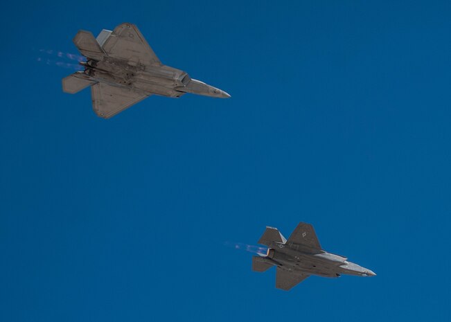 An F-35A Lightning II piloted by Maj. Brad Matherne, 59th Test and Evaluation Squadron F-35 test director, leads an F-22 Raptor in flight during the opening ceremony of the open house at Nellis Air Force Base, Nev., Nov. 8, 2014. The inclusion of the Joint Strike Fighter in the open house marked the first public display of the aircraft at Nellis AFB. (U.S. Air Force photo by Staff Sgt. Siuta B. Ika)