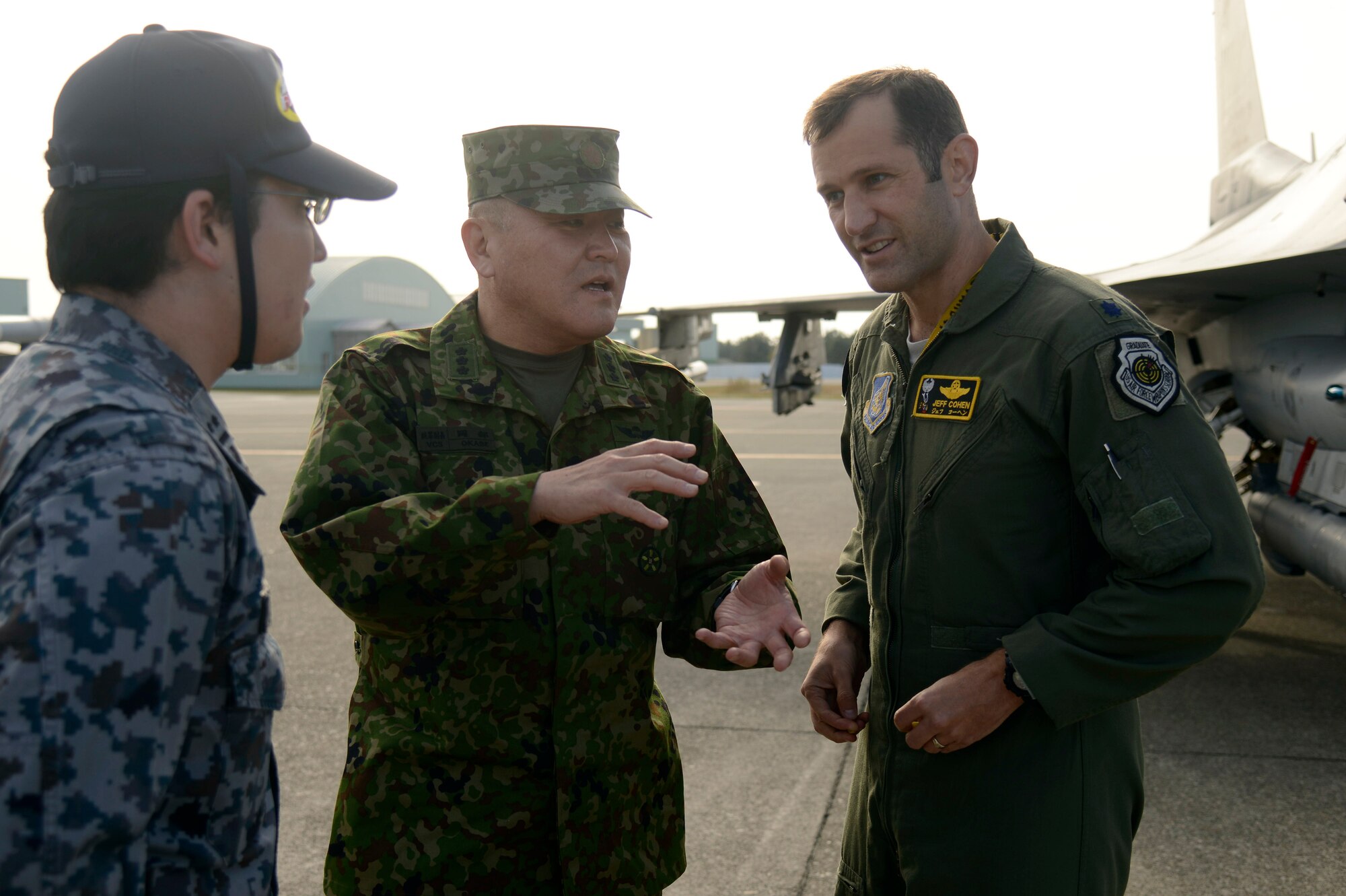 U.S. Air Force Lt. Col. Jeffrey Cohen (right), 14th Fighter Squadron commander, speaks to Lt. Gen. Toshiya Okabe (center), Japanese Ground Self Defense Force deputy chief of joint staff, with the help of a JASDF translator (left) at Komatsu Air Base, Japan, Nov. 10, 2014. Cohen and pilots from the 14 FS flew F-16s to Komatsu AB to train under the Aviation Training program, which allows U.S. and Japanese forces to further enhance their interoperability and joint partnership. Okabe was on hand to witness the first day of training and received a static display tour of an F-16. (U.S. Air Force photo by Staff Sgt. Alyssa C. Wallace)