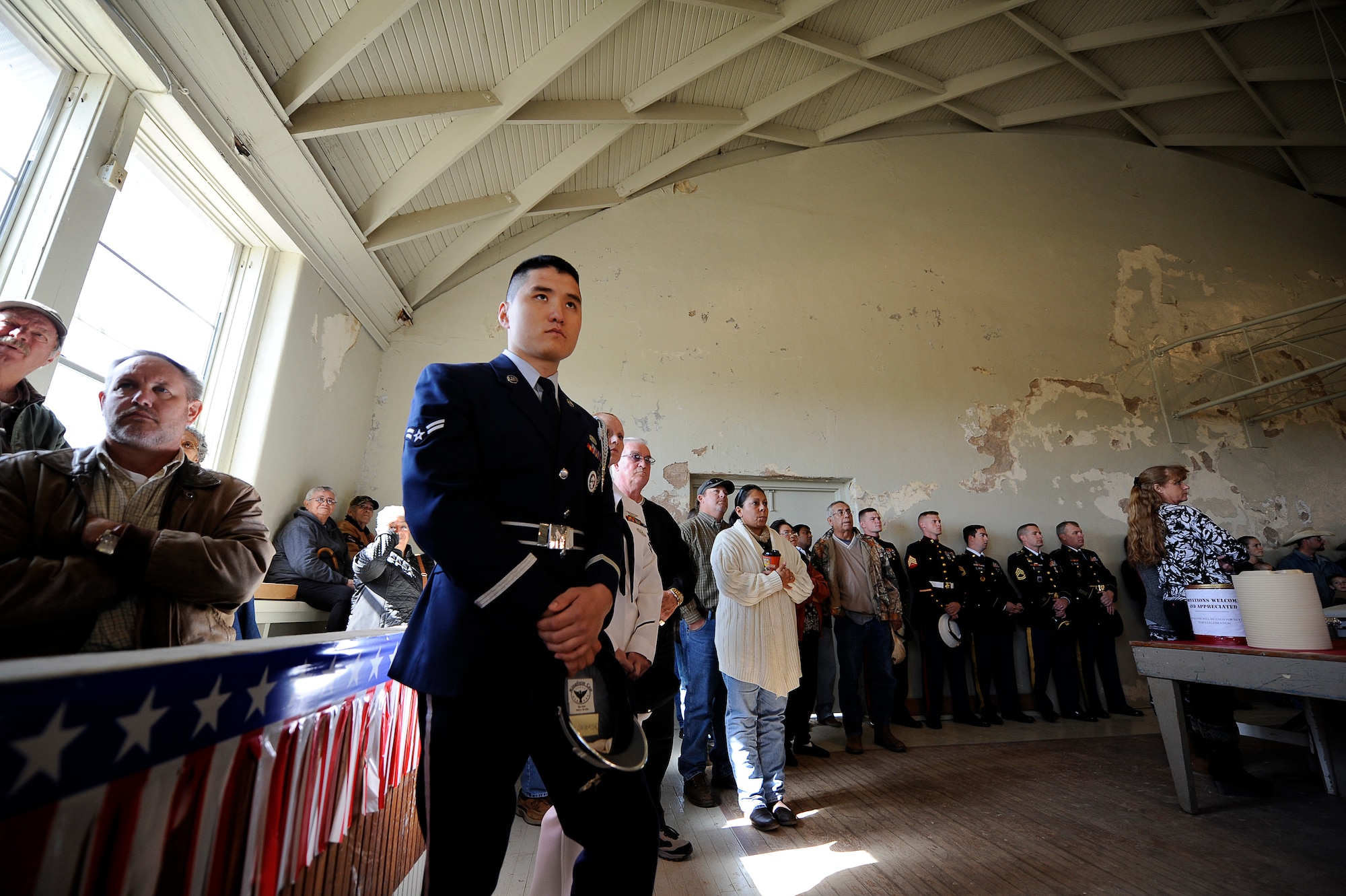 MILLERSVIEW, Texas – Airman 1st Class Aziz N. Sarbashev, Goodfellow Air Force Base Joint Service Color Guardsman, watches the town’s Veterans Day ceremony in the former school gymnasium Nov. 11. The small town has been celebrating Veterans Day as a community since 1919. (U.S. Air Force photo/ Staff Sgt. Austin Knox)
