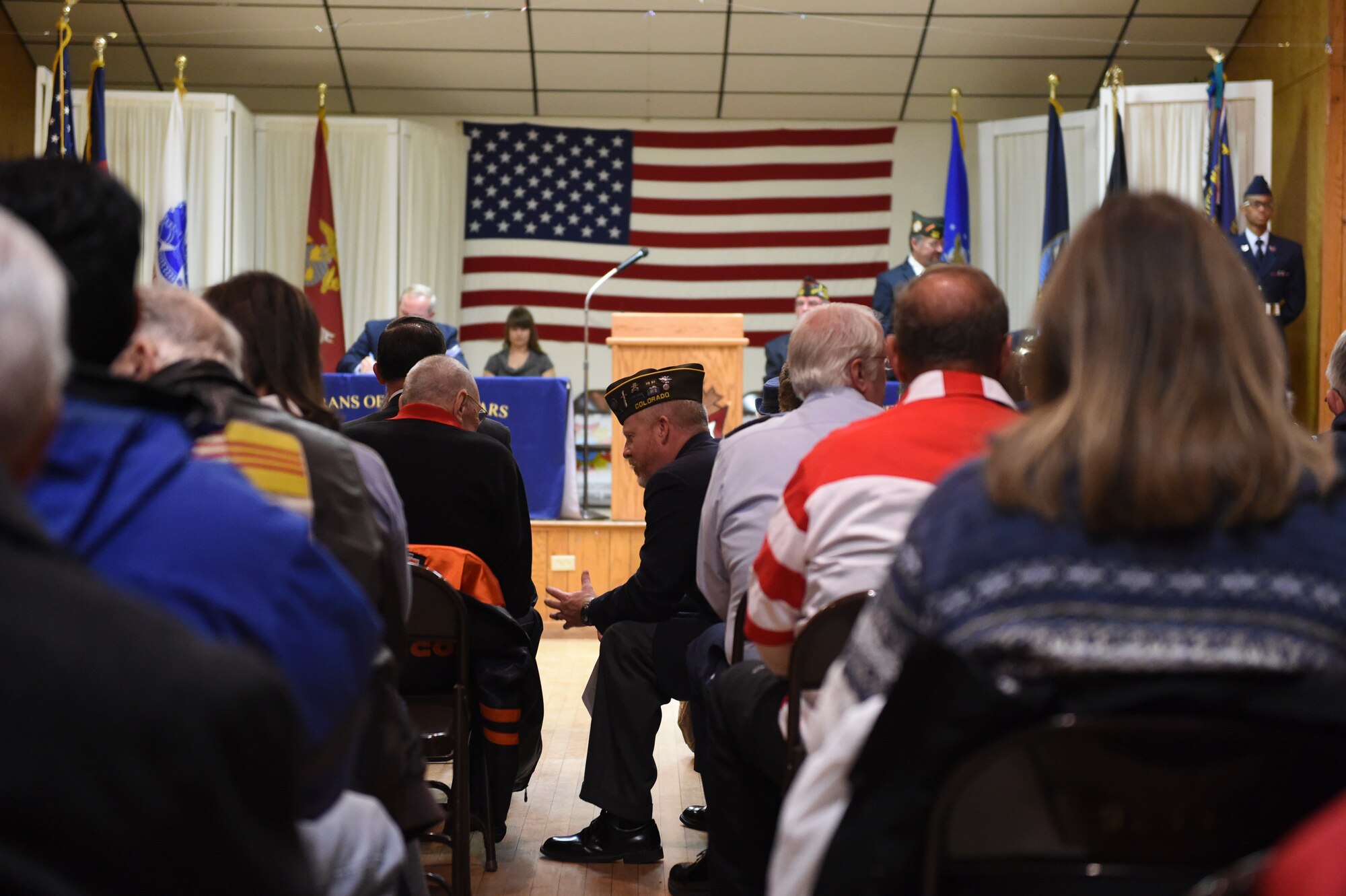 A Colorado Veterans of Foreign Wars member chats with another attendee before commencement of the Fort Logan National Cemetery Veterans Day remembrance service Nov. 11, 2014, at VFW Post 9644 in Englewood, Colo. The 37th annual observance, moved indoors due to inclement weather, included several guest speakers, patriotic music and a wreath ceremony in honor of fallen service members. (U.S. Air Force photo by 1st Lt. Trevor Zakrzewski/Released)