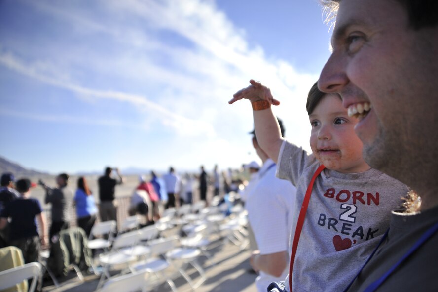 Jared Hardy holds his son Jacob, 2, as he points toward the U.S. Air Force Aerial Demonstration Team Thunderbirds during their performance as part of the Nellis Air Force Base 2014 Open House at Nellis AFB, Nevada, Nov. 8, 2014. The open house is a two-day event depicting America's aviation history and displaying some of the nation's military aircraft, such as the P-51 Mustang, the B-1 Lancer, the F-22 Raptor, and many others. (U.S. Air Force photo by Airman 1st Class Christian Clausen/Released)