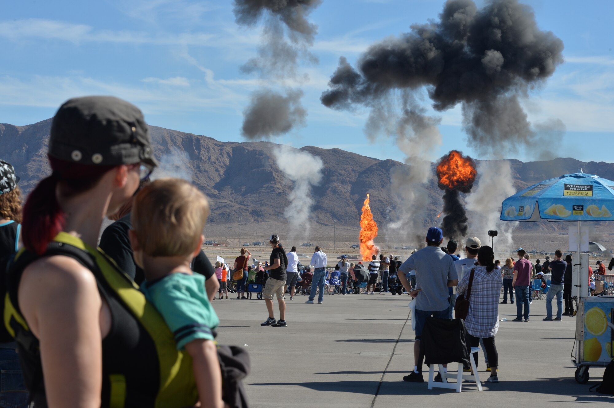 Spectators watch explosions during an air to ground demonstration with A-10 Thunderbolts, F-15E Eagles, HH-60 Pave Hawks, and ground forces during the Nellis Air Force Base 2014 Open House at Nellis AFB, Nevada, Nov. 9, 2014. The two-day event included aerial demonstrations from various aircraft, as well as a performance by the United States Air Force Aerial Demonstration Team Thunderbirds. (U.S. Air Force photo by Tech. Sgt. Nadine Barclay)