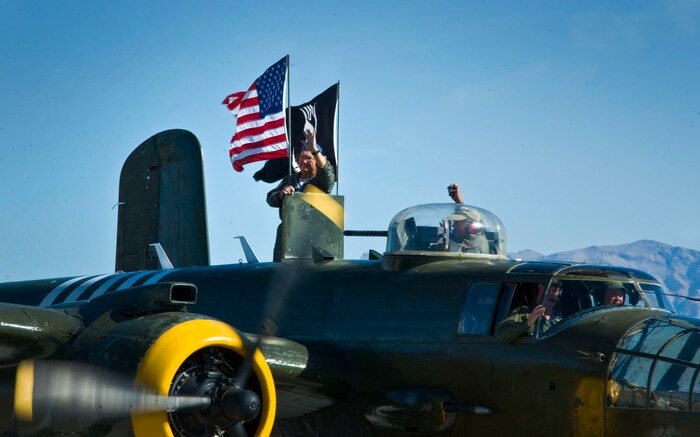Crewmembers of a B-25J Mitchell performing at the Nellis Open House wave to the crowd as the aircraft taxis down the flight line at Nellis Air Force Base, Nev., Nov. 9, 2014. The performing B-25J, dubbed “Executive Sweet,” is maintained by volunteers whose goal is to preserve the aviation legacy of World War II veterans. (U.S. Air Force photo by Airman 1st Class Rachel Loftis)