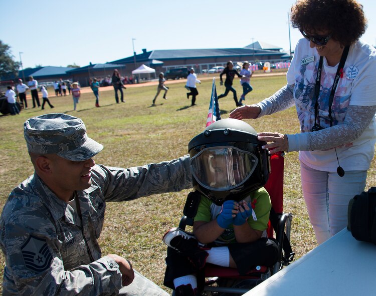 Master Sgt. Pyryt, 33rd Aircraft Maintenance Squadron, helps his child try on explosive ordnance disposal helmet during a Veteran’s Day celebration held at Riverside Elementary in Crestview, Fla., Nov. 10.  Airmen from EOD, life support, honor guard and 6th Ranger Training Battalion Soldiers were on hand to interact with the children in this first-ever school event.  (U.S. Air Force photo/Tech. Sgt. Jasmin Taylor)