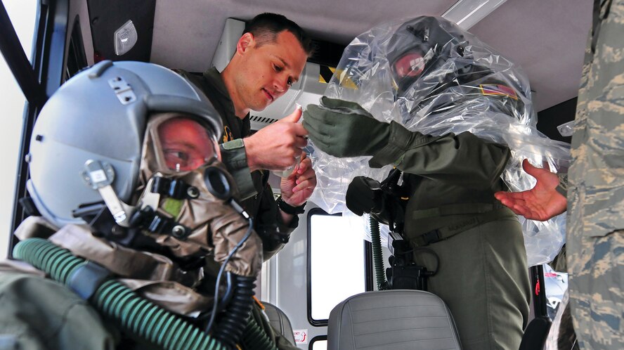 WRIGHT-PATTERSON AIR FORCE BASE, Ohio – Maj. Jonathan Askins, 89th Airlift Squadron C-17 pilot, helps fellow pilots in the unit with their protective gear while training on chemical, biological, radiological and nuclear defense (CBRN) techniques during a training flight Oct. 4, 2014. The crew wears filtered breathing apparatus and is covered in plastic while outside the aircraft, to protect against any falling contaminants. (U.S. Air Force photo/Tech. Sgt. Frank Oliver)