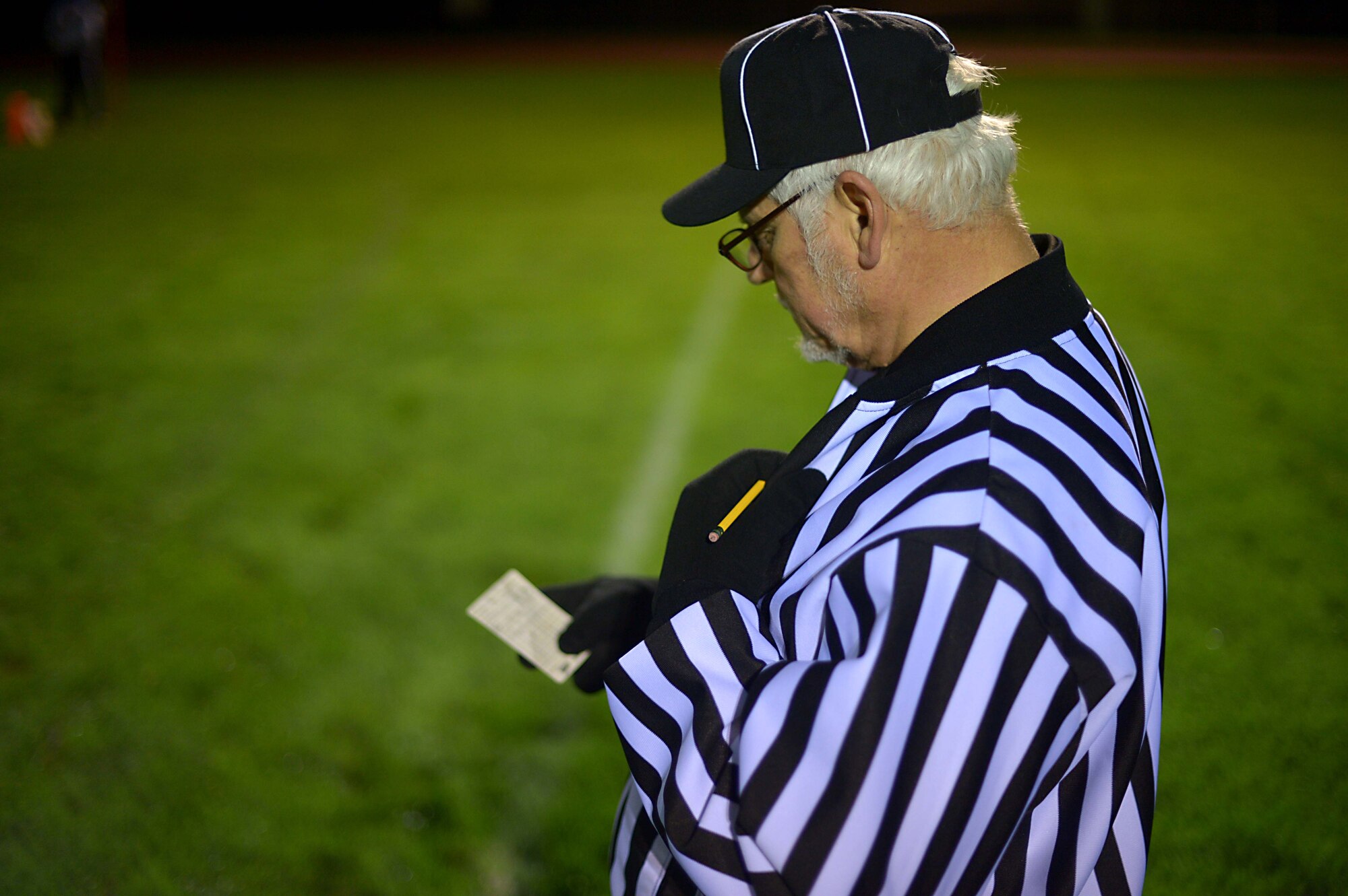 A football referee reviews his scorecard during the intramural football championship game at Spangdahlem Air Base, Germany, Nov. 10, 2014. After calling several timeouts, the 52nd Communications Squadron battled back and forth against the 52nd Civil Engineer Squadron, pushing them into overtime. (U.S. Air Force photo by Airman 1st Class Kyle Gese/Released)
