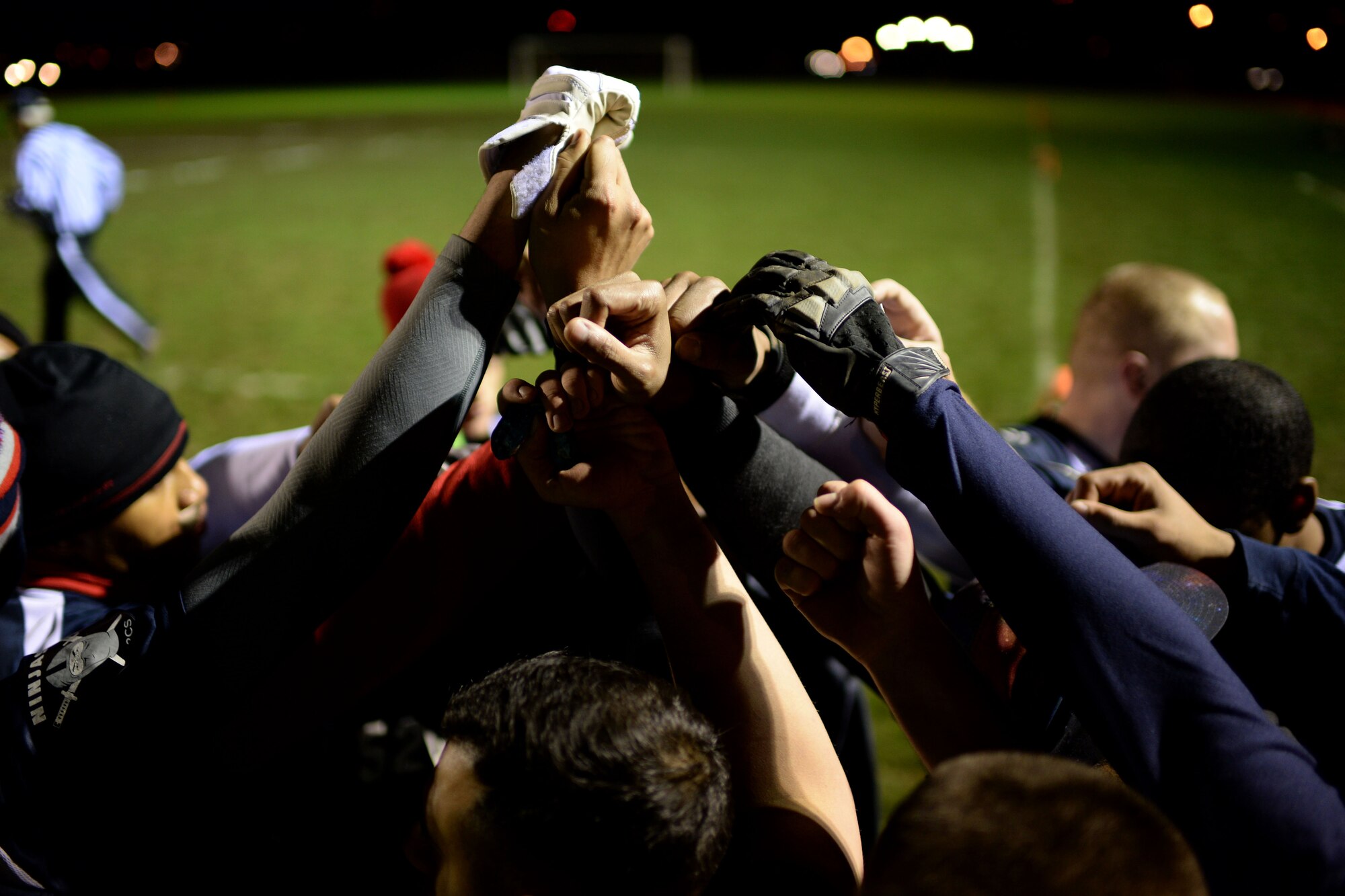 Airmen from the 52nd Communications Squadron join hands for a team chant during the intramural football championship game at Spangdahlem Air Base, Germany, Nov. 10, 2014. The football season brought Airmen together to raise squadron morale; exercising social and physical fitness fundamentals. (U.S. Air Force photo by Staff Sgt. Daryl Knee/Released)