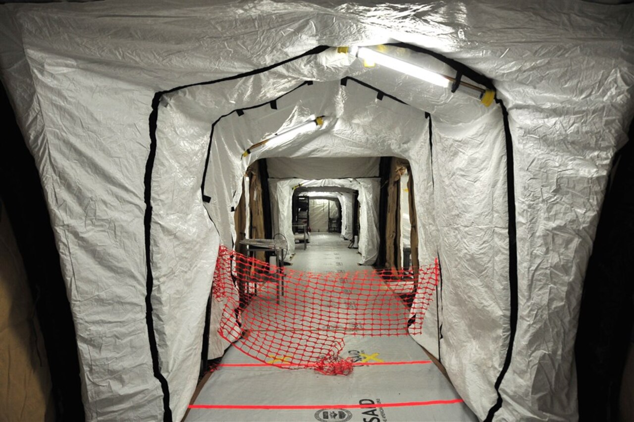 Simple red lines on the floor are what mark the boundary between the low-risk zone and the high-risk zone in the Monrovia Medical Unit, a facility designed for health care workers who become infected with the virus. U.S. Army photo by Sgt. 1st Class Nathan Hoskins, Joint Forces Command, United Assistance Public Affairs