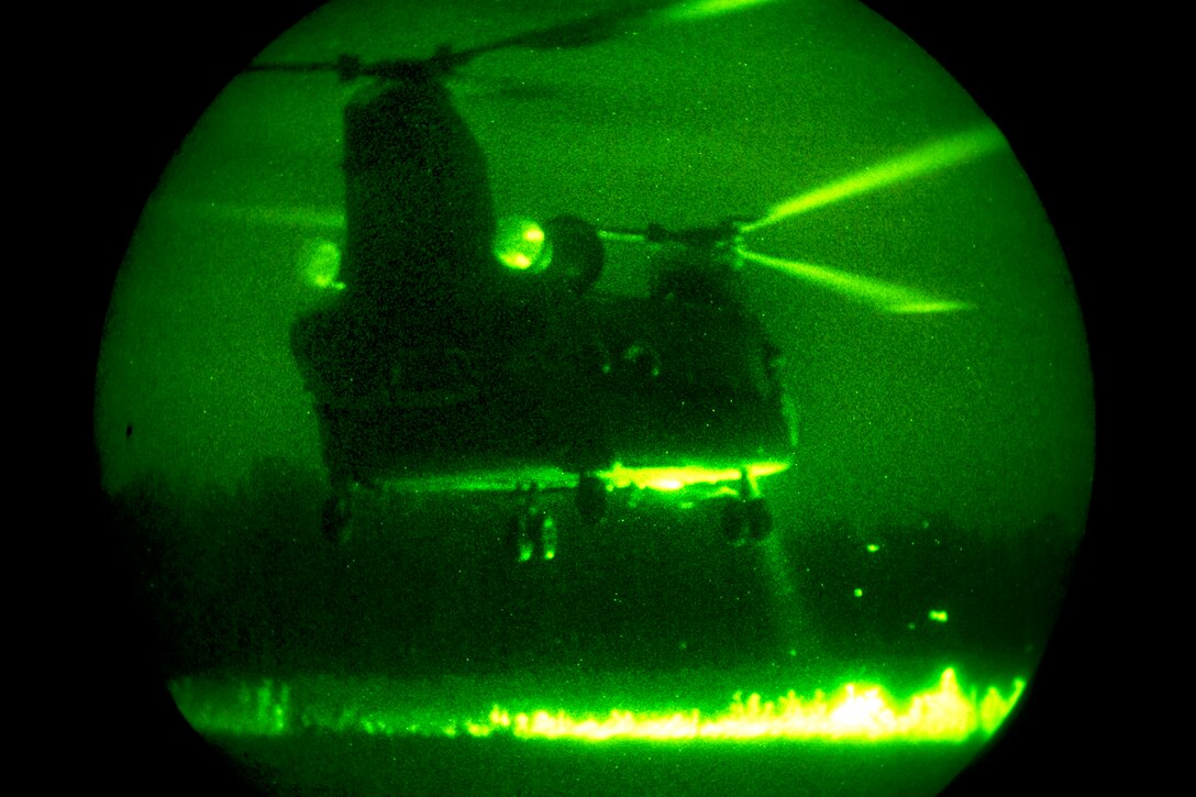 As seen through a night-vision device, a CH-47 Chinook helicopter lands ...