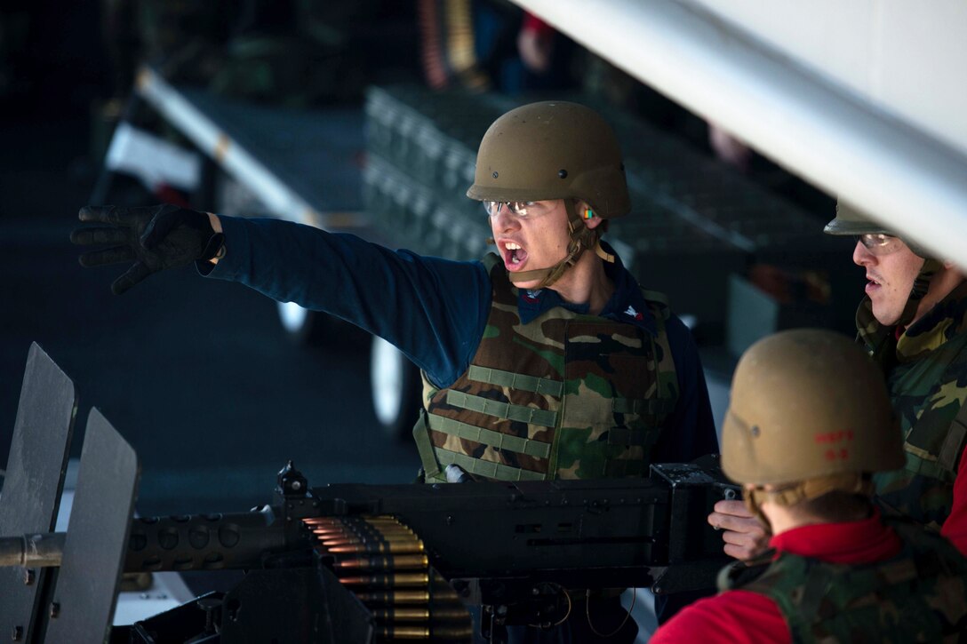 Navy Petty Officer 2nd Class Chance Adams, left, instructs Seaman Justin Coleman during a .50-caliber gun firing exercise on the fantail of the Nimitz-class aircraft carrier USS John C. Stennis in Bremerton, Wash., Nov. 8, 2014. Adams is a gunner's mate, and Coleman is an aviation ordnanceman airman.