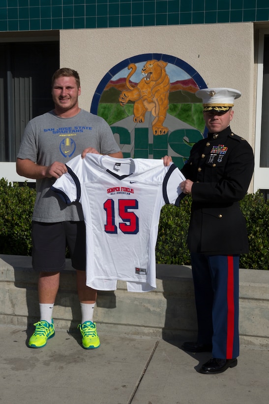 Kyle Hoppe, offensive center for Chaparral High School receives his Semper Fidelis All-American Bowl jersey from Maj. Brian Donlon, commanding officer of Marine Corps Recruiting Station San Diego in the weight room in front of his fellow football players at Chaparral High School, Nov. 13, 2014. Hoppe is among approximately 100 student athletes from across the nation selected to participate in the game at the StubHub Center in Carson, Calif., Jan. 4, 2015. 