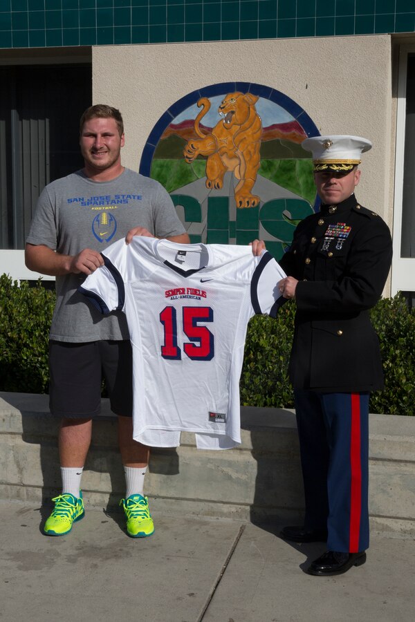 Kyle Hoppe, offensive center for Chaparral High School receives his Semper Fidelis All-American Bowl jersey from Maj. Brian Donlon, commanding officer of Marine Corps Recruiting Station San Diego in the weight room in front of his fellow football players at Chaparral High School, Nov. 13, 2014. Hoppe is among approximately 100 student athletes from across the nation selected to participate in the game at the StubHub Center in Carson, Calif., Jan. 4, 2015. 