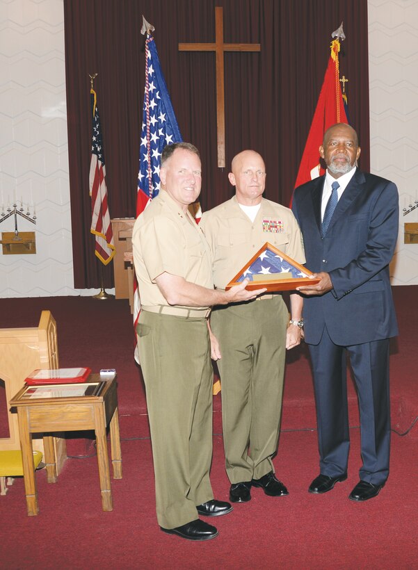 Maj. Gen. John J. Broadmeadow, commanding general, presents Gerald Dixson (right), an American flag, during his retirement ceremony at the Chapel of the Good Shepherd, here, in October. They and Sgt. Maj. Joseph M. Davenport (center) are all with Marine Corps Logistics Command.
