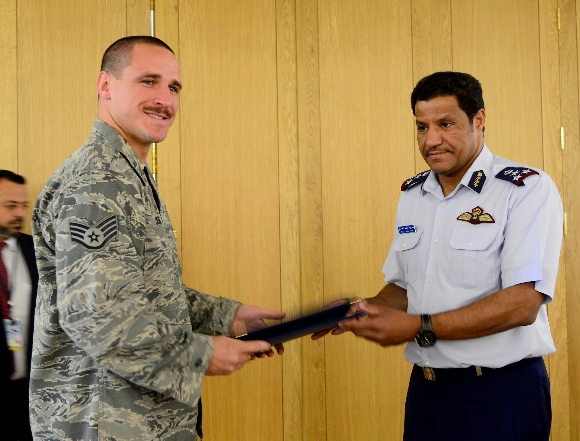 Brig. Gen. 'Ali Bayyat Al-'Asiri, Al Udeid Air Base commander/OC Transportation Wing, presents U.S. Air Force Staff Sgt. Matthew Duggan, 379th Expeditionary Civil Engineer Squadron firefighter, with a certificate during the Qatar Emiri Air Force’s Air Lift Wing’s C-17 Globemaster III 5th year anniversary ceremony Nov. 7, 2014, at Al Udeid Air Base, Qatar. The firefighters were presented with certificates of appreciation for their help in putting out a C-17 fire Sept. 6, here. Eighteen fire rescue personnel were on the scene and involved in the mitigation efforts. (U.S. Air Force photo by Senior Airman Kia Atkins)