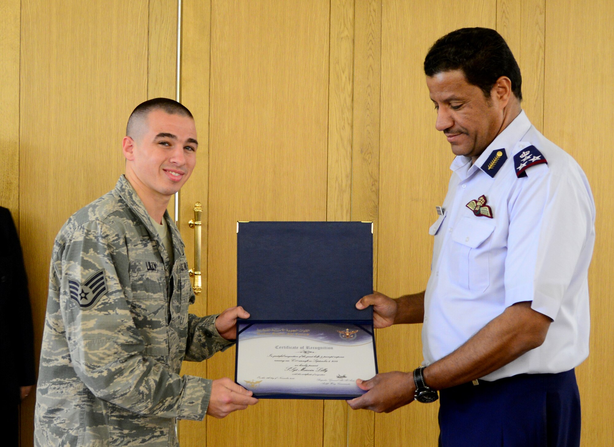 Brig. Gen. 'Ali Bayyat Al-'Asiri, Al Udeid Air Base commander/OC Transportation Wing, presents U.S. Air Force Staff Sgt. Marvin Lilly, 379th Expeditionary Civil Engineer Squadron firefighter, with a certificate during the Qatar Emiri Air Force’s Air Lift Wing’s C-17 Globemaster III 5th year anniversary ceremony Nov. 7, 2014, at Al Udeid Air Base, Qatar. The firefighters were presented with certificates for their help in putting out a C-17 fire Sept. 6, here. Crash fire crews responded out to the C-17 to extinguish the fire limiting the damage to the aircraft.  (U.S. Air Force photo by Senior Airman Kia Atkins)