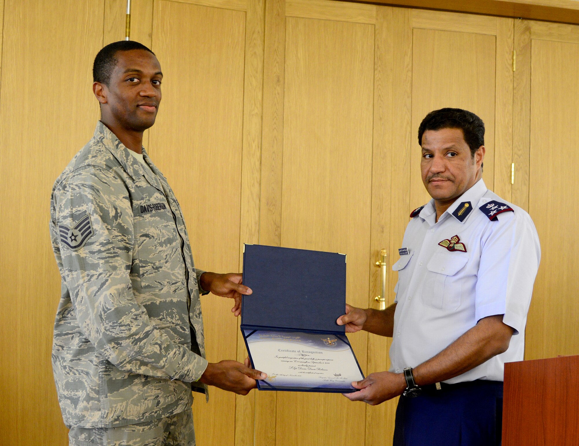 Brig. Gen. 'Ali Bayyat Al-'Asiri, Al Udeid Air Base commander/OC Transportation Wing, presents U.S. Air Force Staff Sgt. Devin Davis-Roberson, 379th Expeditionary Civil Engineer Squadron firefighter, with a certificate during the Qatar Emiri Air Force’s Air Lift Wing’s C-17 Globemaster III 5th year anniversary ceremony Nov. 7, 2014, at Al Udeid Air Base, Qatar. The firefighters were presented with certificates of appreciation for the part they played in putting out a C-17 fire Sept. 6, here. (U.S. Air Force photo by Senior Airman Kia Atkins)