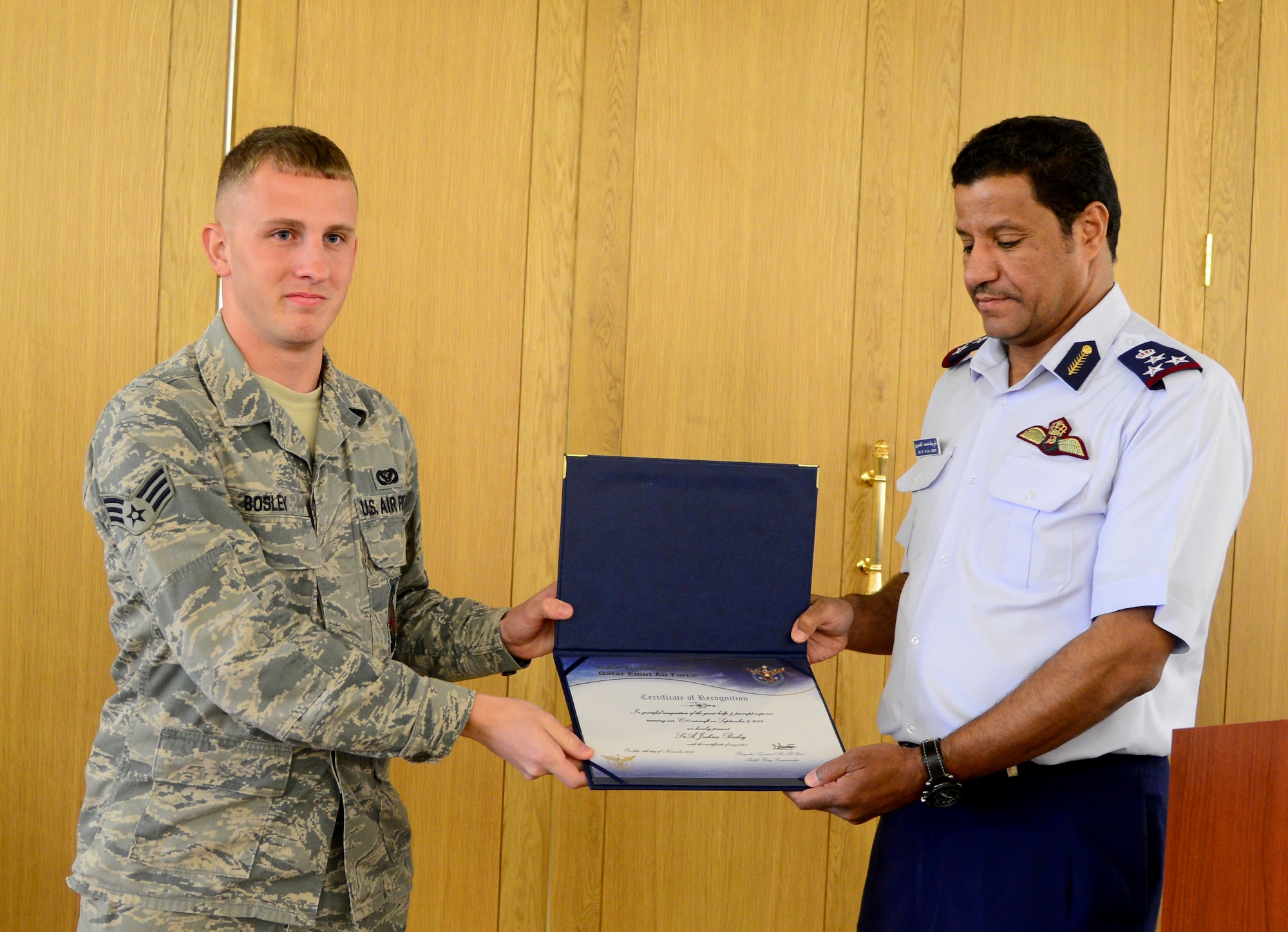 Brig. Gen. 'Ali Bayyat Al-'Asiri, Al Udeid Air Base commander/OC Transportation Wing presents U.S. Air Force Senior Airman Joshua Bosley, 379th Expeditionary Civil Engineer Squadron firefighter, with a certificate of appreciation during the Qatar Emiri Air Force’s Air Lift Wing’s C-17 5th year anniversary ceremony Nov. 7, 2014, at Al Udeid Air Base, Qatar. Bosley and his other fellow firefighters were presented with these certificates for their help in putting out a fire on a C-17 Sept. 6, here. (U.S. Air Force photo by Senior Airman Kia Atkins)