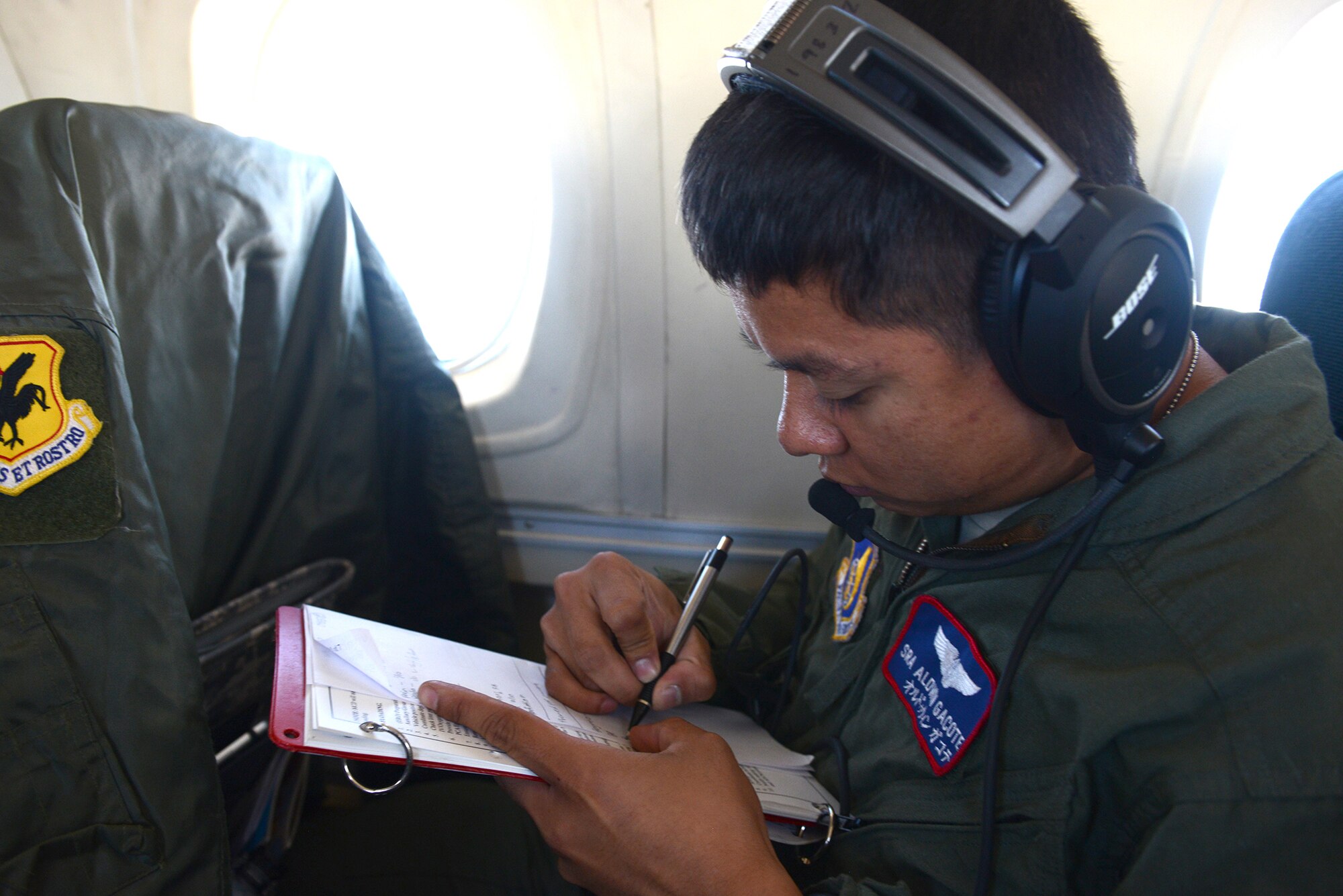 Senior Airman Aldwin Gacote, 18th Aeromedical Evacuation Squadron medical technician, records vital information for two simulated patients aboard a C-12 Huron over Kadena Air Base, Japan, Nov. 12, 2014. The 18 AES took part in Exercise Keen Sword 2015 testing their medical capabilities aboard smaller aircraft. (U.S. Air Force photo by Airman 1st Class David C. Danford/Released)