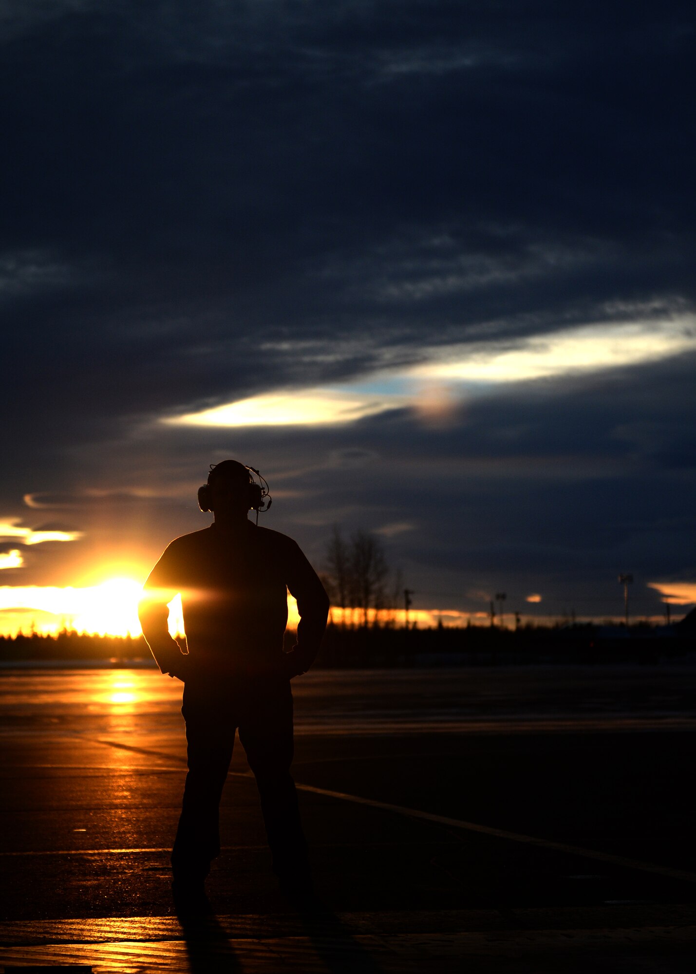 U.S. Air Force Staff Sgt. Richard Garner, a 354th Aircraft Maintenance Squadron crew chief, stands in the sunset and communicates with an Airman conducting an engine test on an F-16 Fighting Falcon fighter aircraft at Eielson Air Force Base, Alaska, Nov. 12, 2014. The maintainers completed the final test prior to the jet being used for training by pilots with the 18th Aggressor Squadron. (U.S. Air Force photo by Staff Sgt. Shawn Nickel/Released)