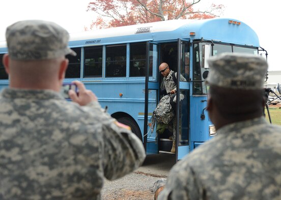 U.S. Army Soldiers look on as Service members disembark a bus upon arrival at Langley Transit Center at Langley Air Force Base, Va., Nov. 13, 2014. Ninety Service members from multiple branches of the Armed Forces will undergo a 21-day controlled monitoring period at the transit center after returning from fighting the spread of Ebola in West Africa in support of Operation United Assistance. (U.S. Air Force photo by Staff Sgt. Jason J. Brown/Released)