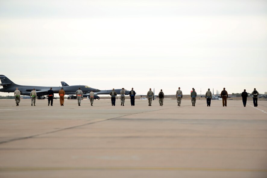 Dyess Airmen from the 7th Maintenance Group conduct a Foreign Object Debris (FOD) walk down the flight line Nov. 5, 2014, at Dyess Air Force Base, Texas. FOD walks are performed to remove debris from areas that aircraft and other flight line equipment operate on. Debris could cause significant damage if it comes in contact with moving mechanical parts. (U.S. Air Force photo by Airman 1st Class Kedesha Pennant/Released)